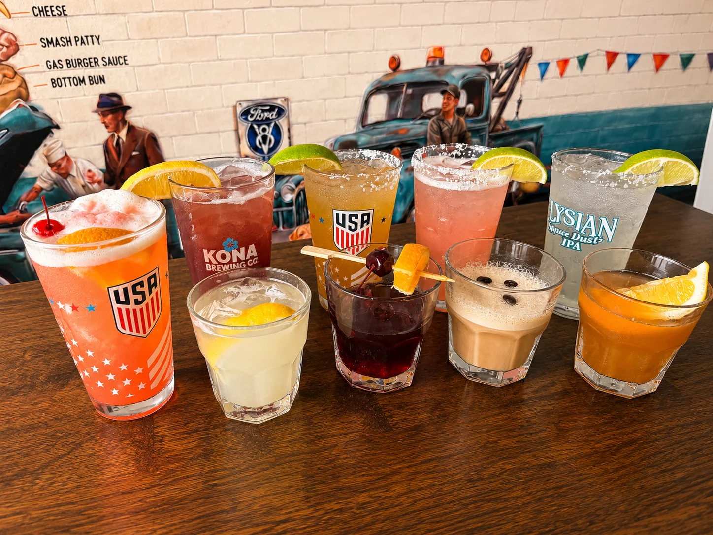Colorful cocktails lined up on a wooden bar counter