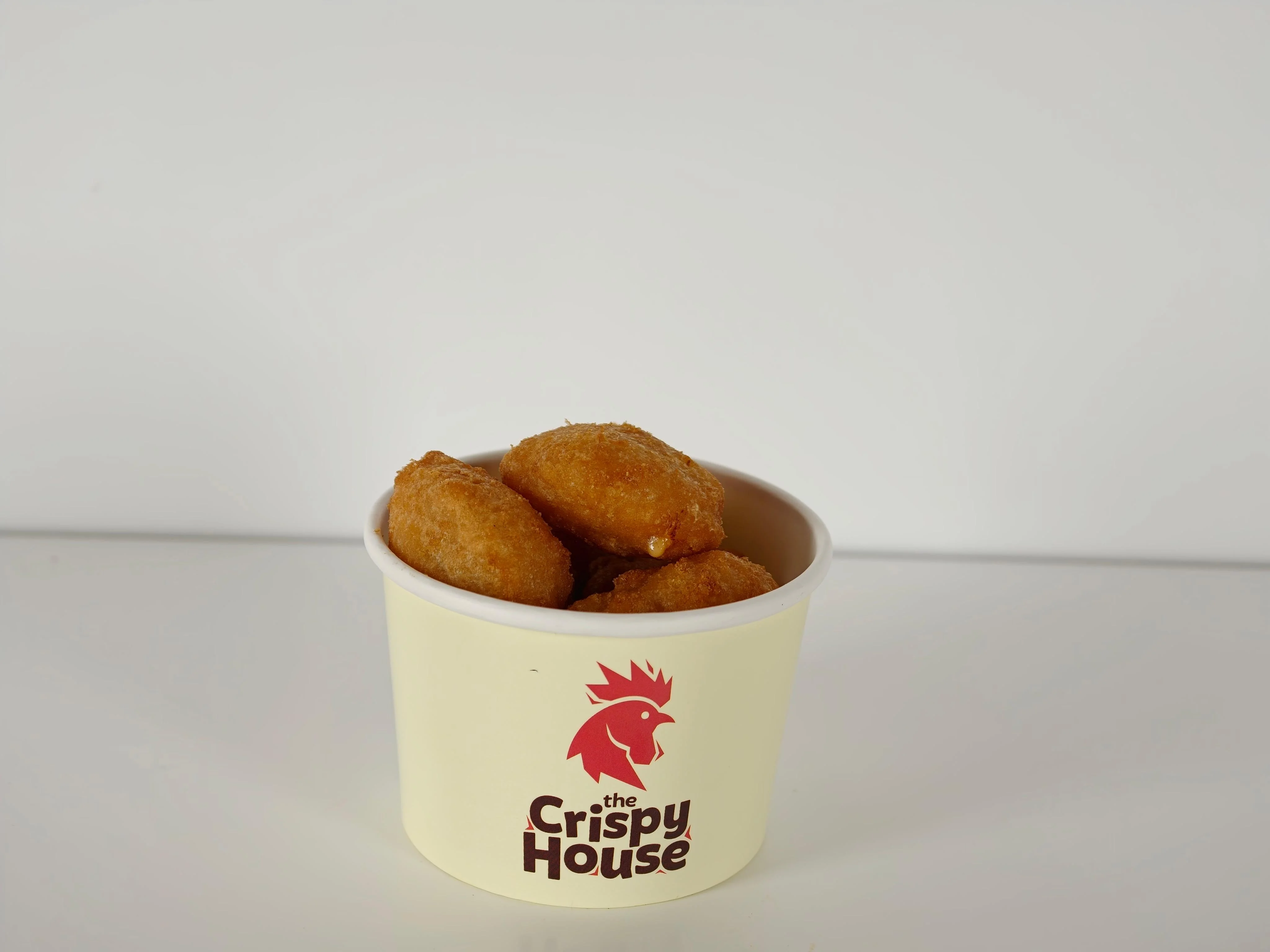 A cup containing several golden-brown cornbread bites, ready to be enjoyed.