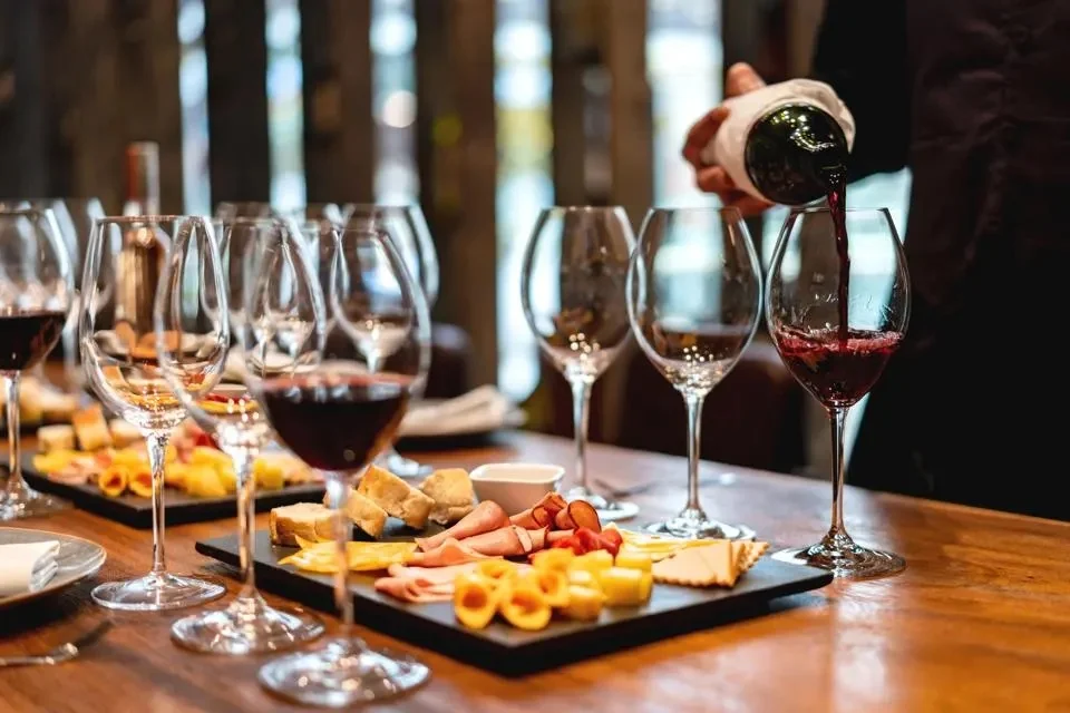 Wine being poured into glasses at a charcuterie board