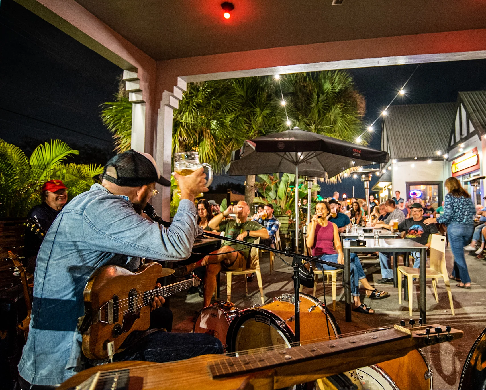 Live music performance at a vibrant outdoor restaurant with a lively crowd.