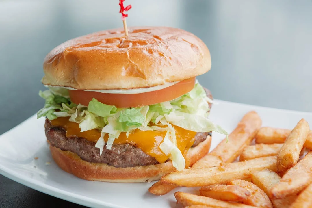 Classic American cheeseburger with fries on a white plate