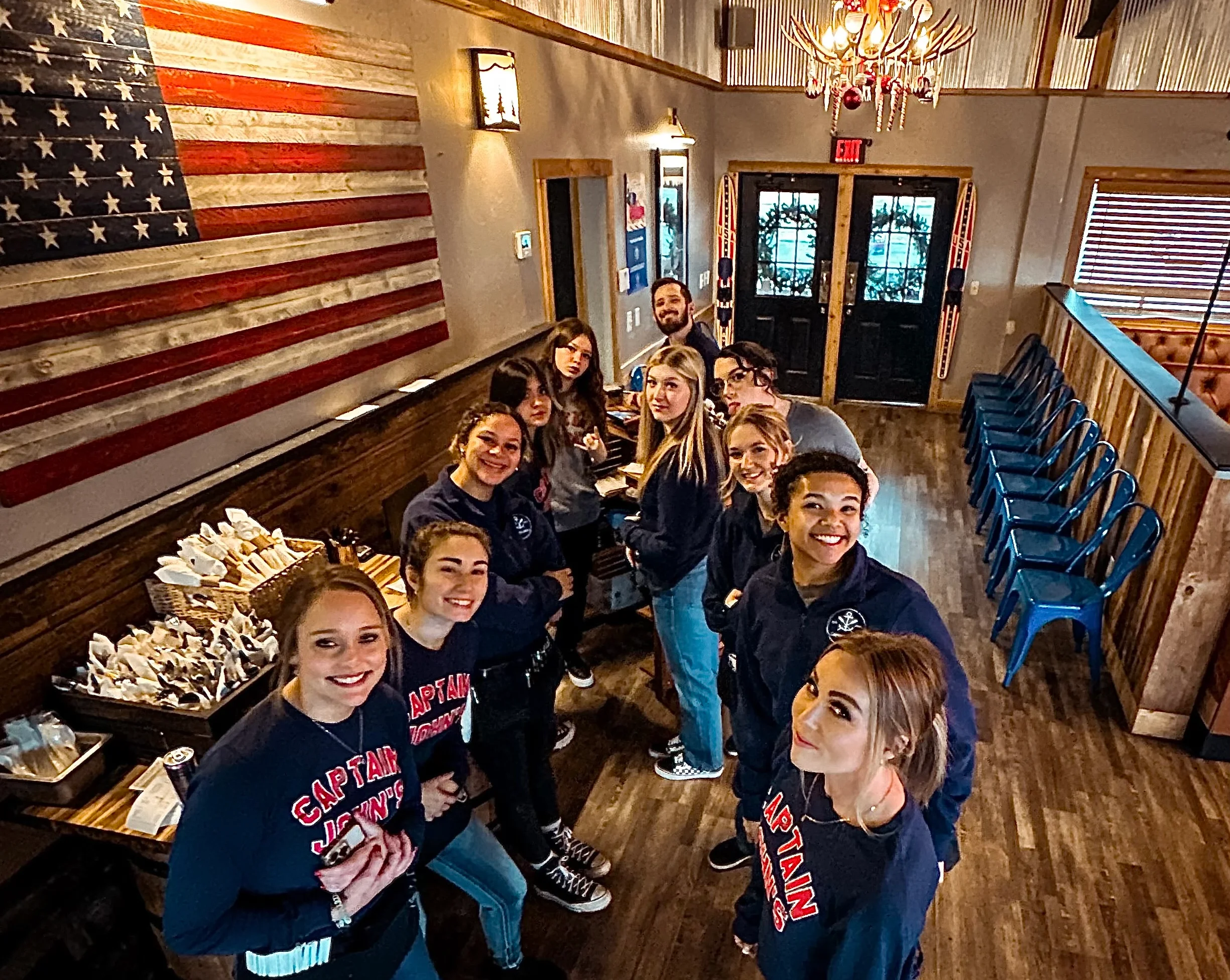 Friendly restaurant staff posing in a rustic dining area with American flag decor