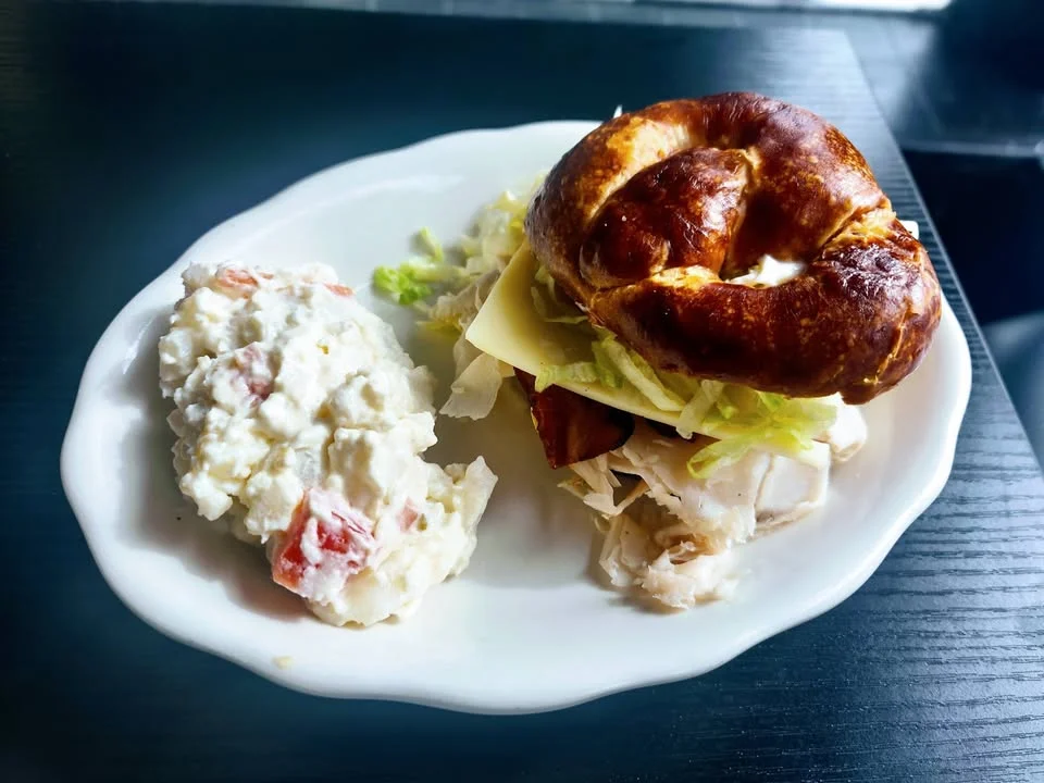 Pretzel sandwich with turkey and salad on a plate