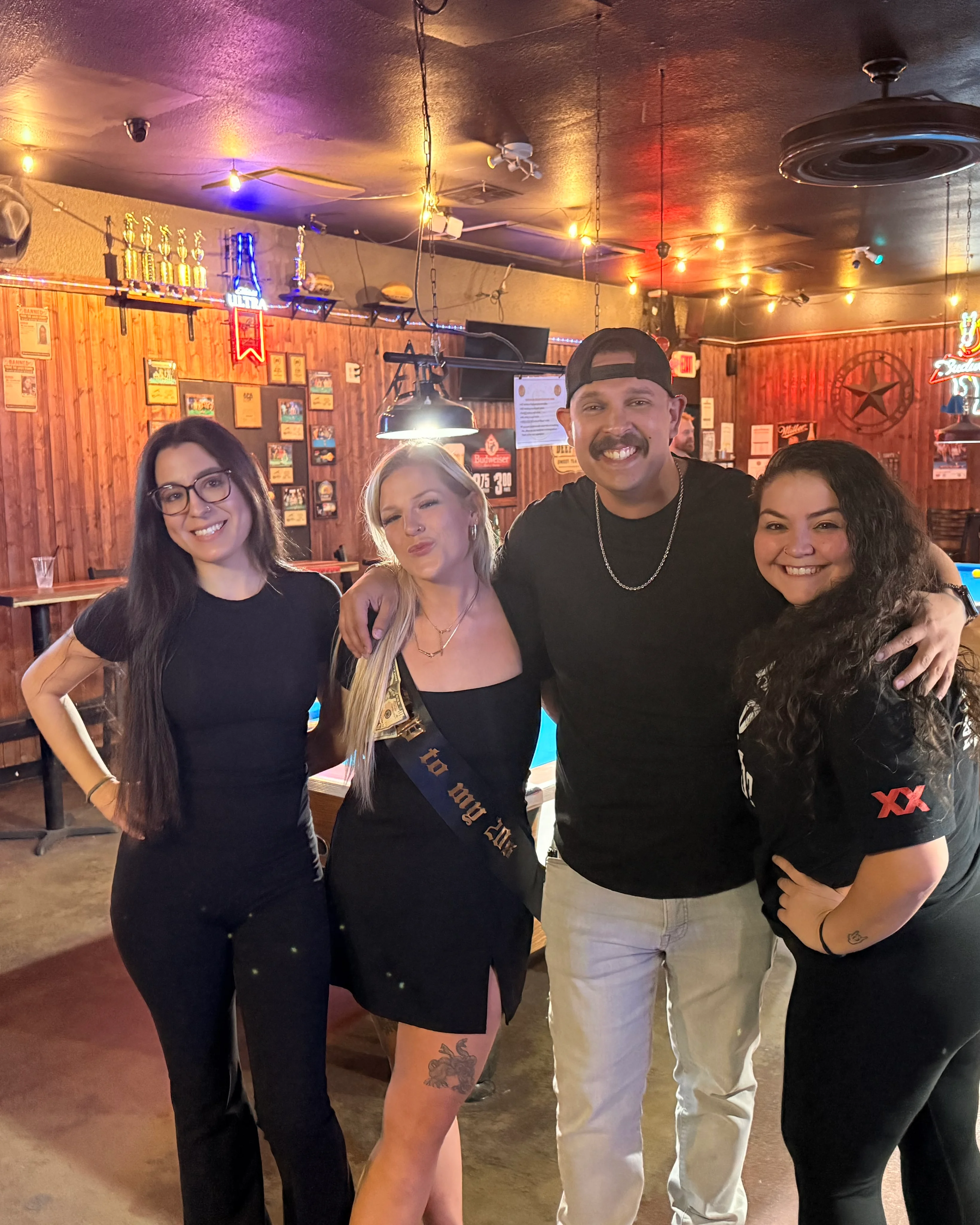 Group of friends posing in a lively bar with pool table