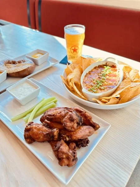 Crispy buffalo wings with nachos and beer in a casual dining setting