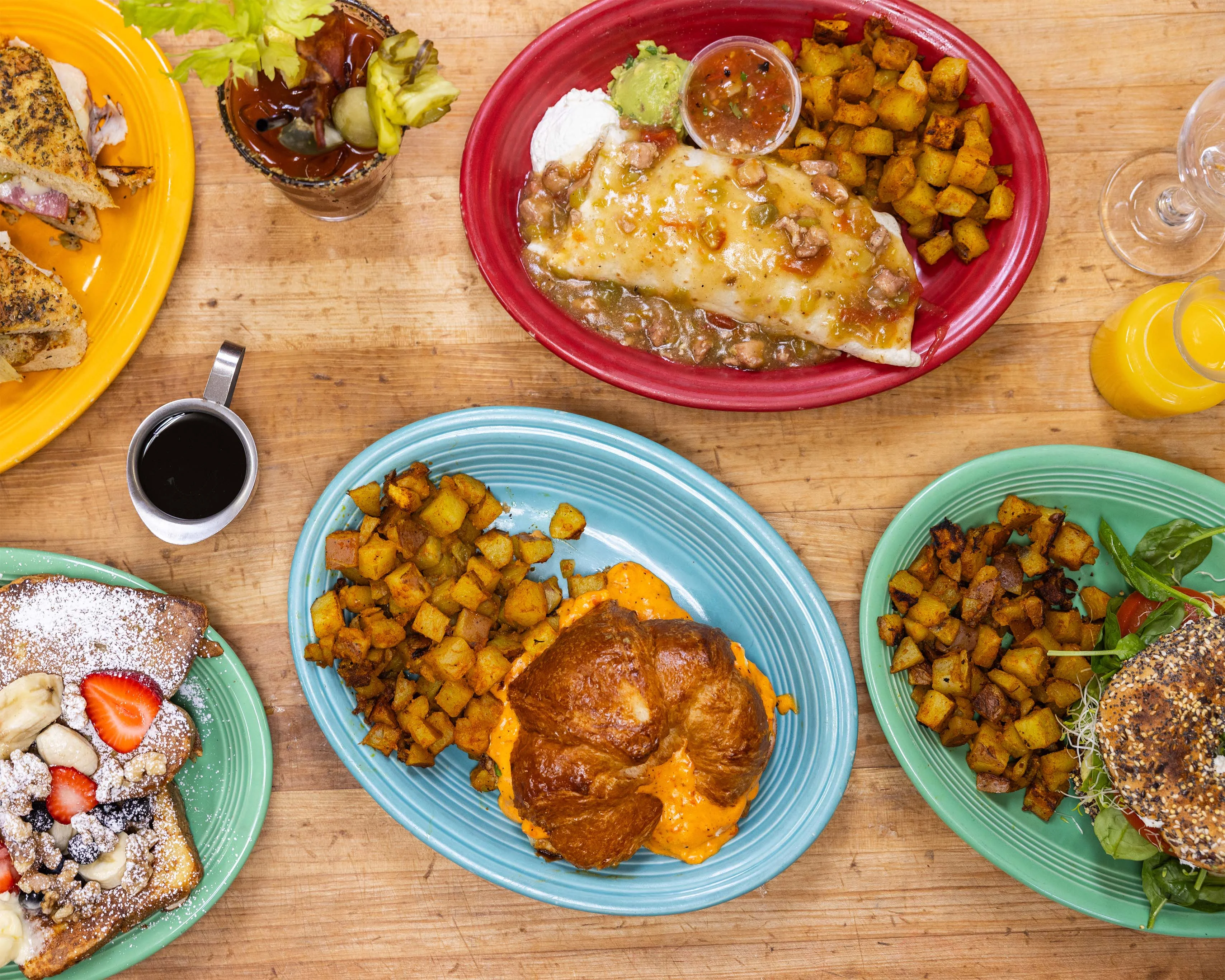 Overhead brunch spread with croissant sandwiches, roasted potatoes, French toast, and salad
