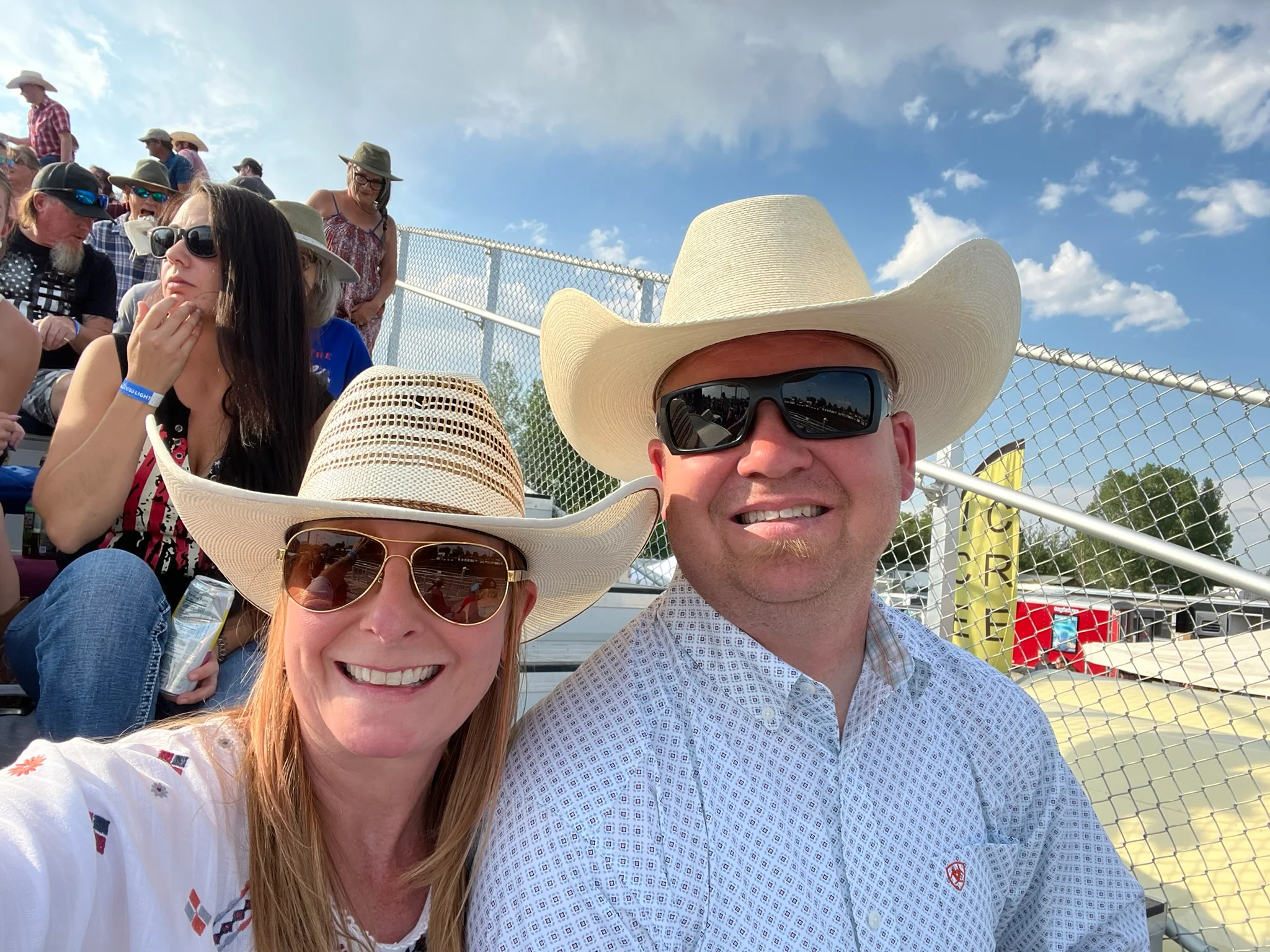 Couple enjoying a sunny day at a rodeo event with cowboy hats