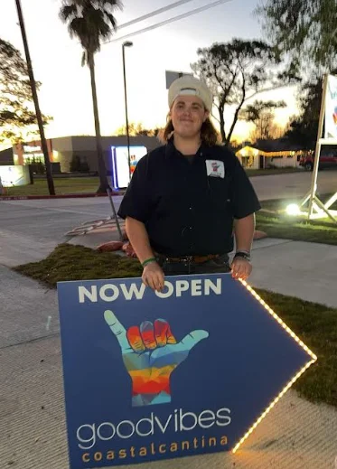 Staff member holding a sign for Good Vibes Coastal Cantina