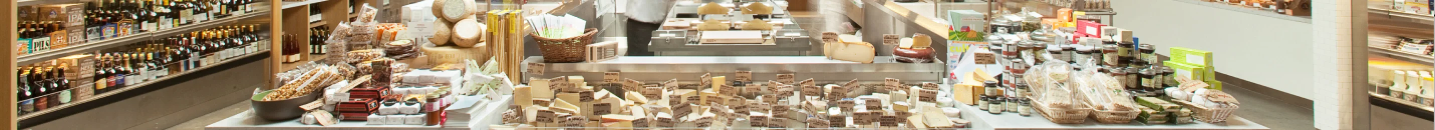 Gourmet food market display with artisanal cheeses and beverages