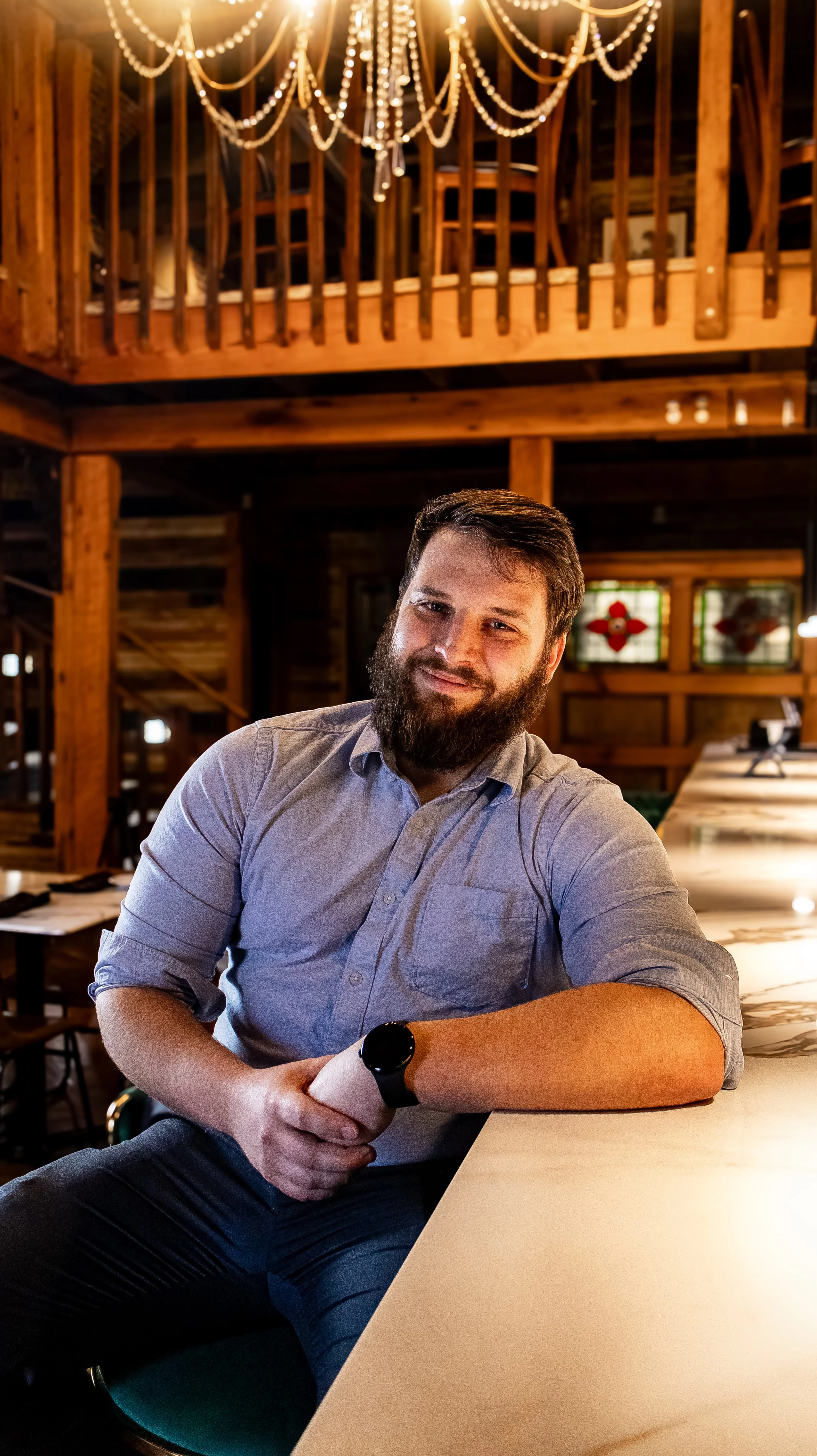 Smiling bartender at a rustic bar counter in a cozy restaurant