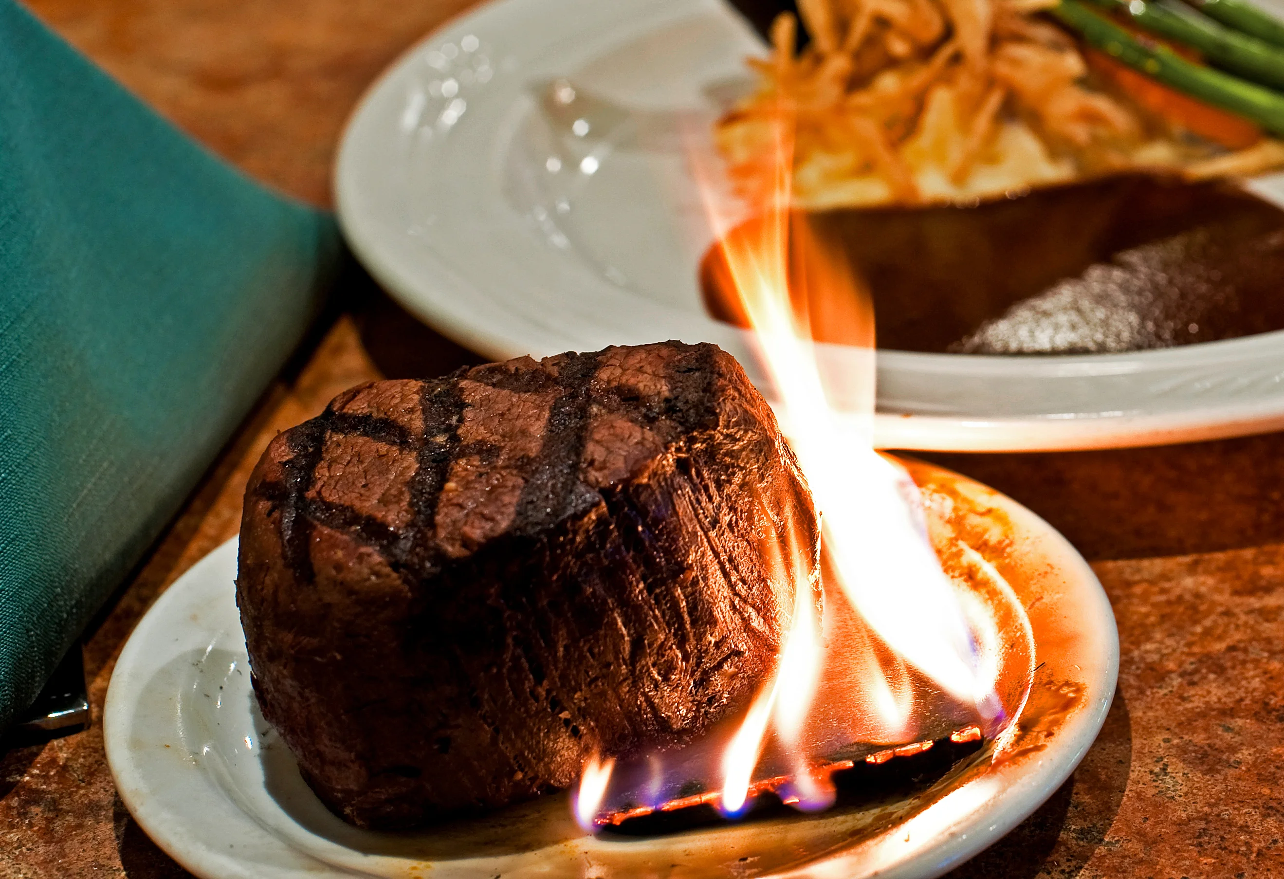 Flaming steak served on a plate in a restaurant