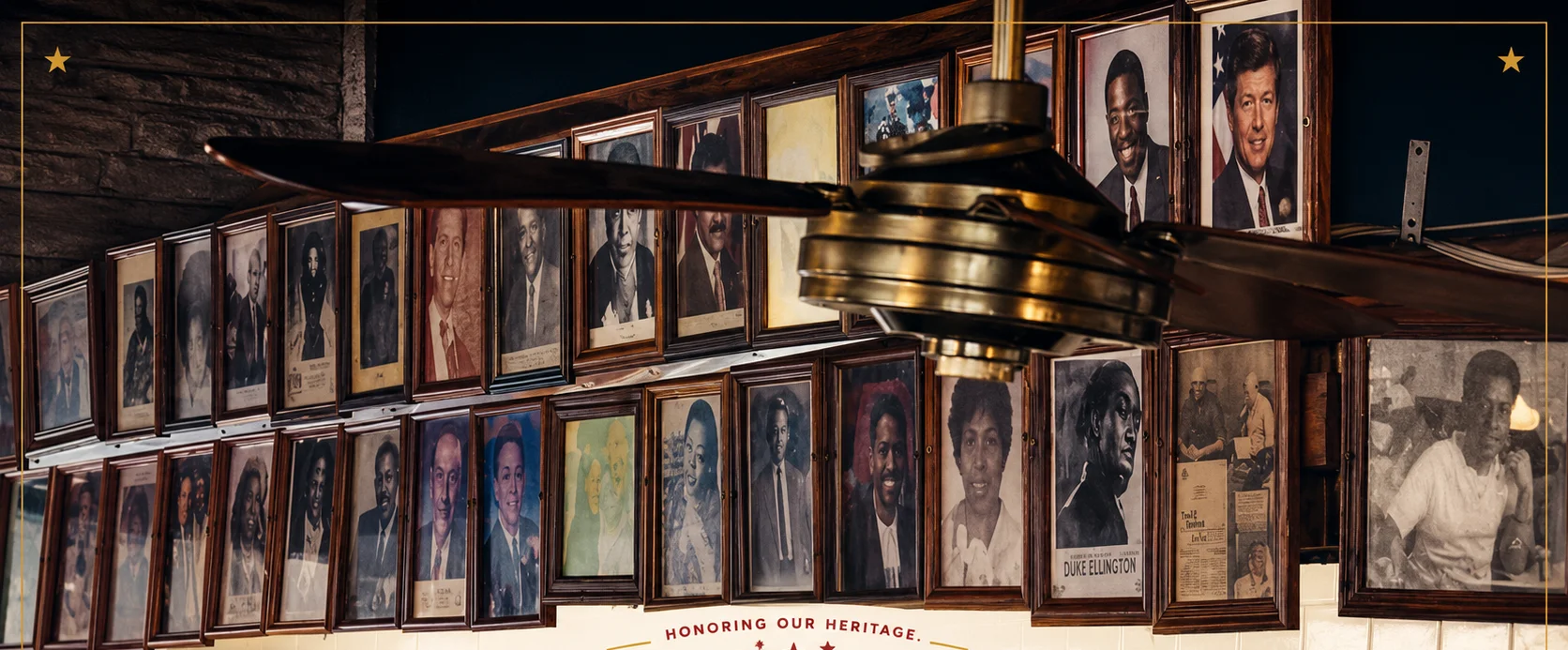 Historic restaurant wall with framed portraits, vintage ceiling fan, and heritage typography