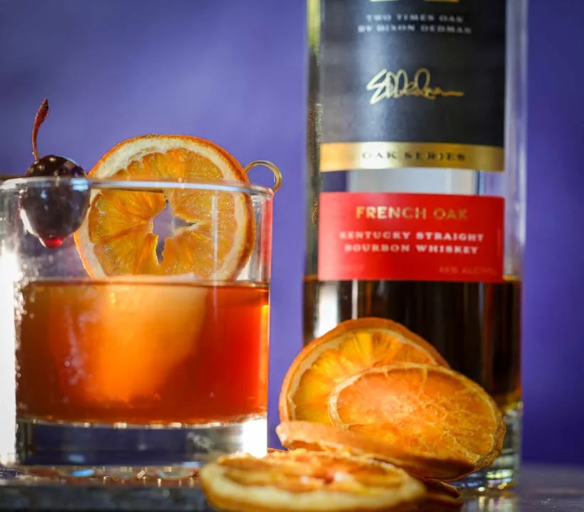 Crafted bourbon cocktail with orange and cherry garnish