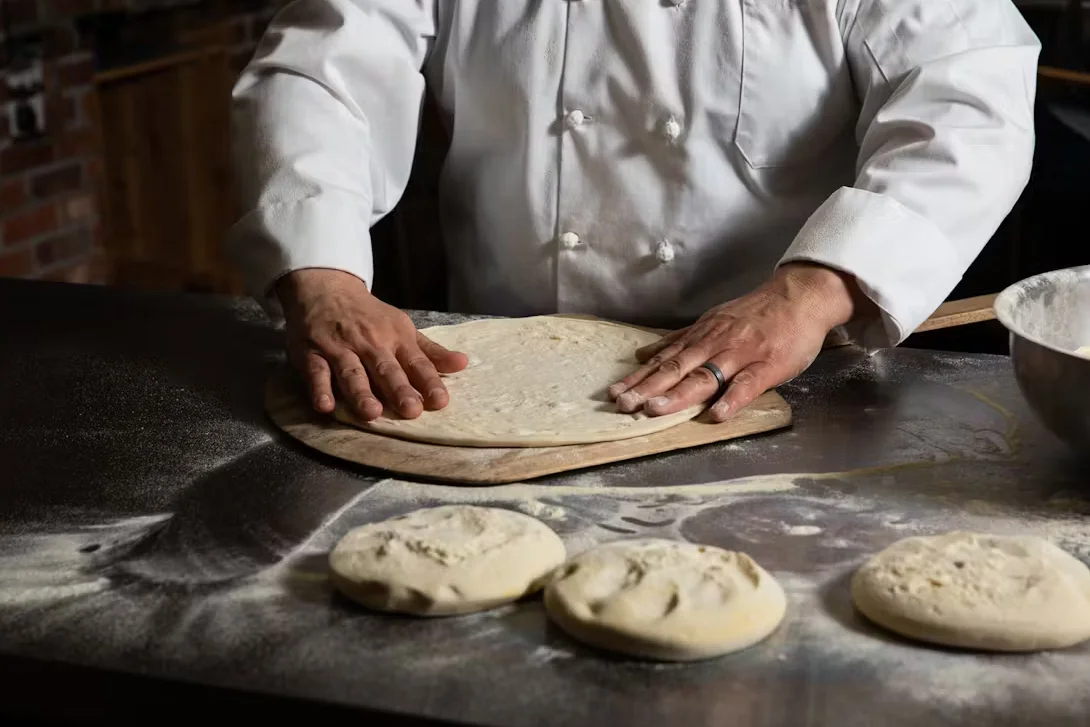 A chef making a perfectly round pizza dough