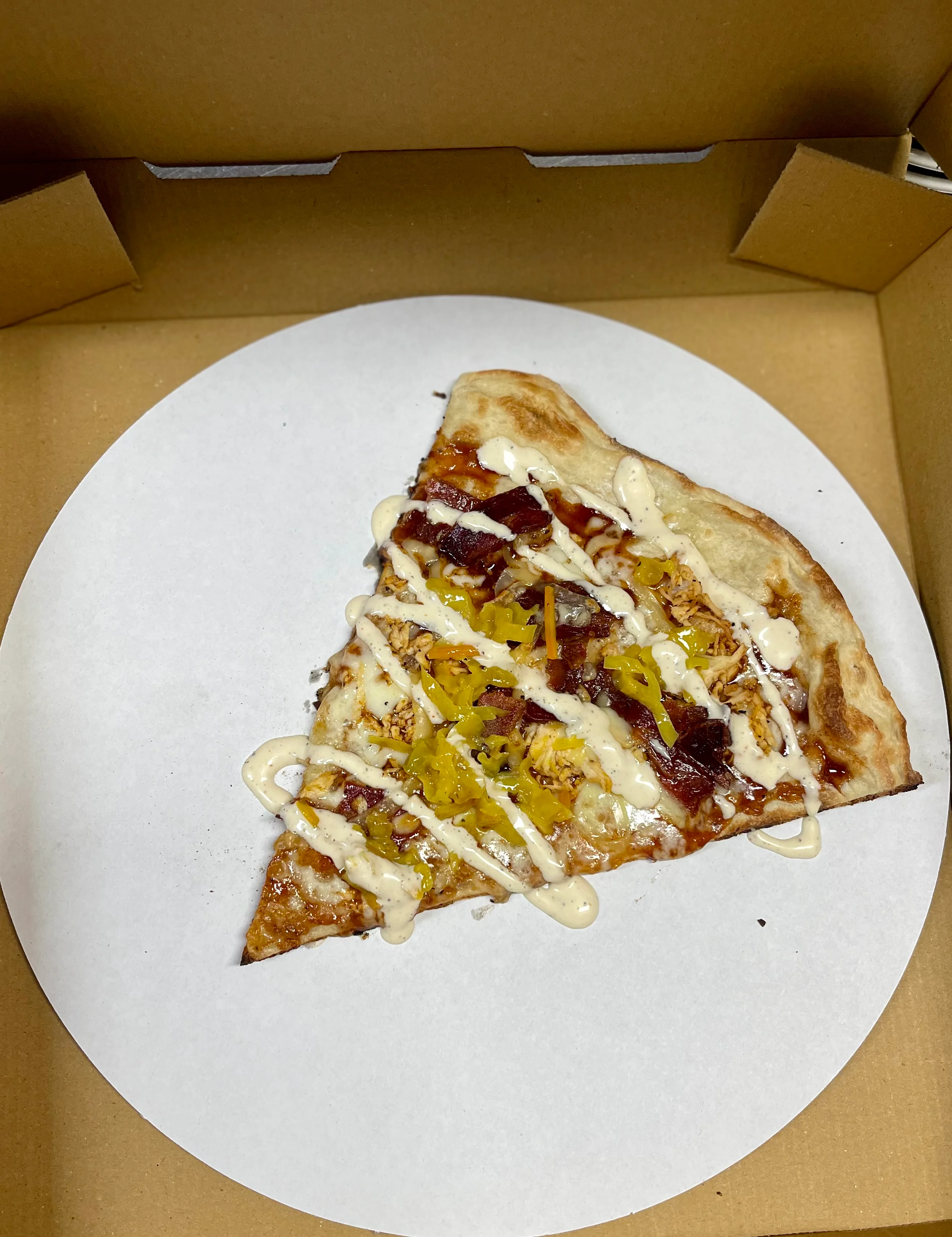 BBQ chicken pizza slice with creamy drizzle
