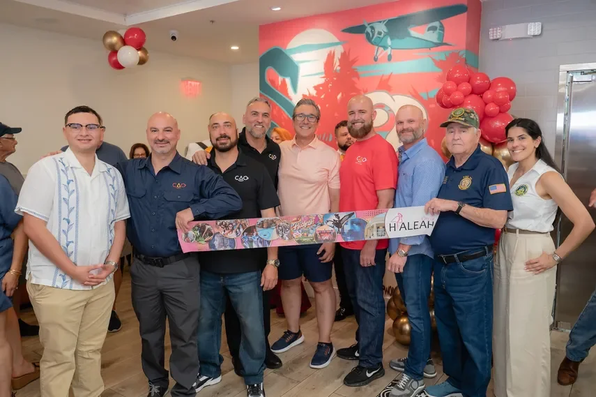Group celebration at a restaurant opening with a colorful mural backdrop
