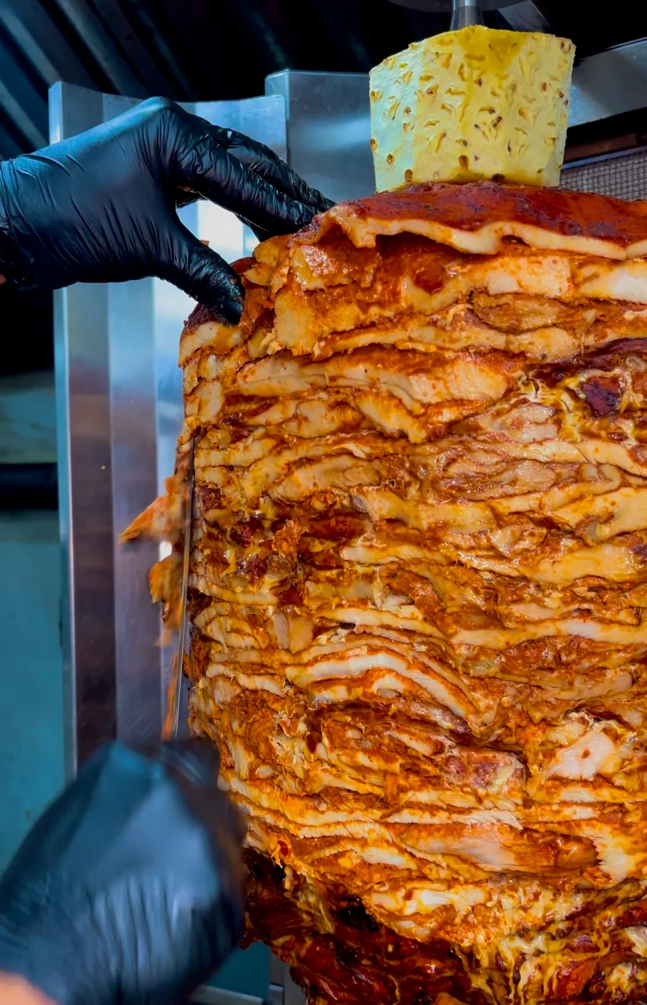 Tacos al pastor with pineapple on a vertical spit