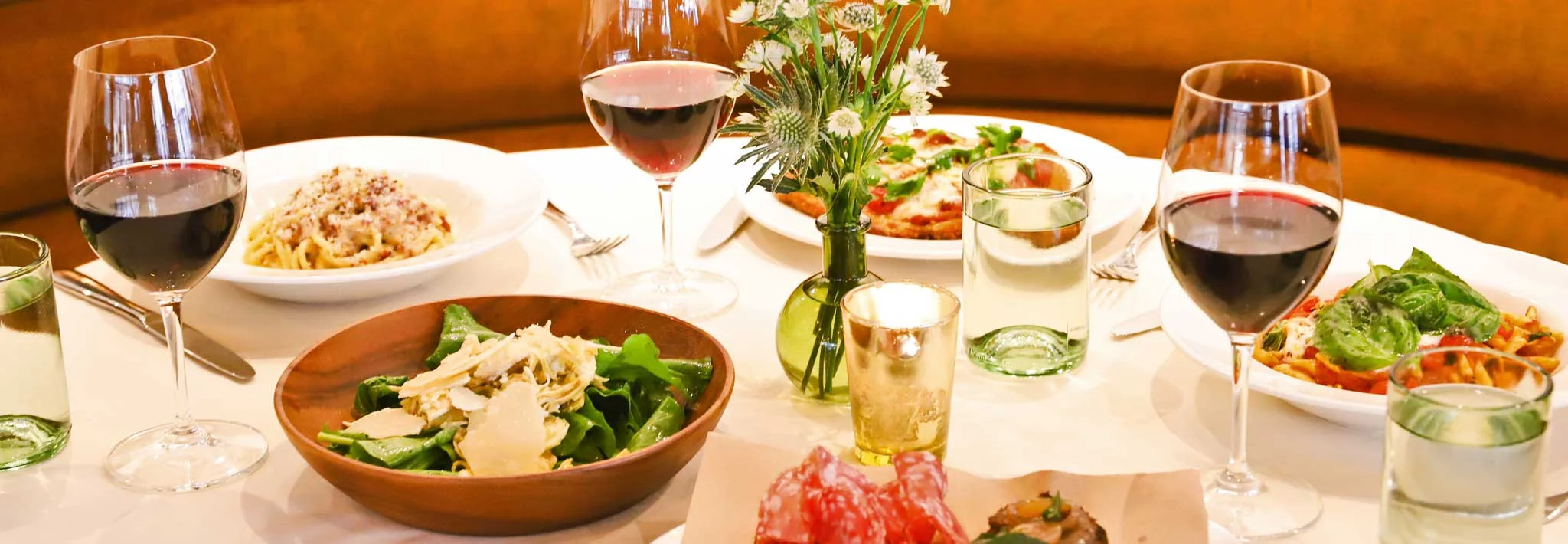 Italian dining table with pasta, salad, and red wine
