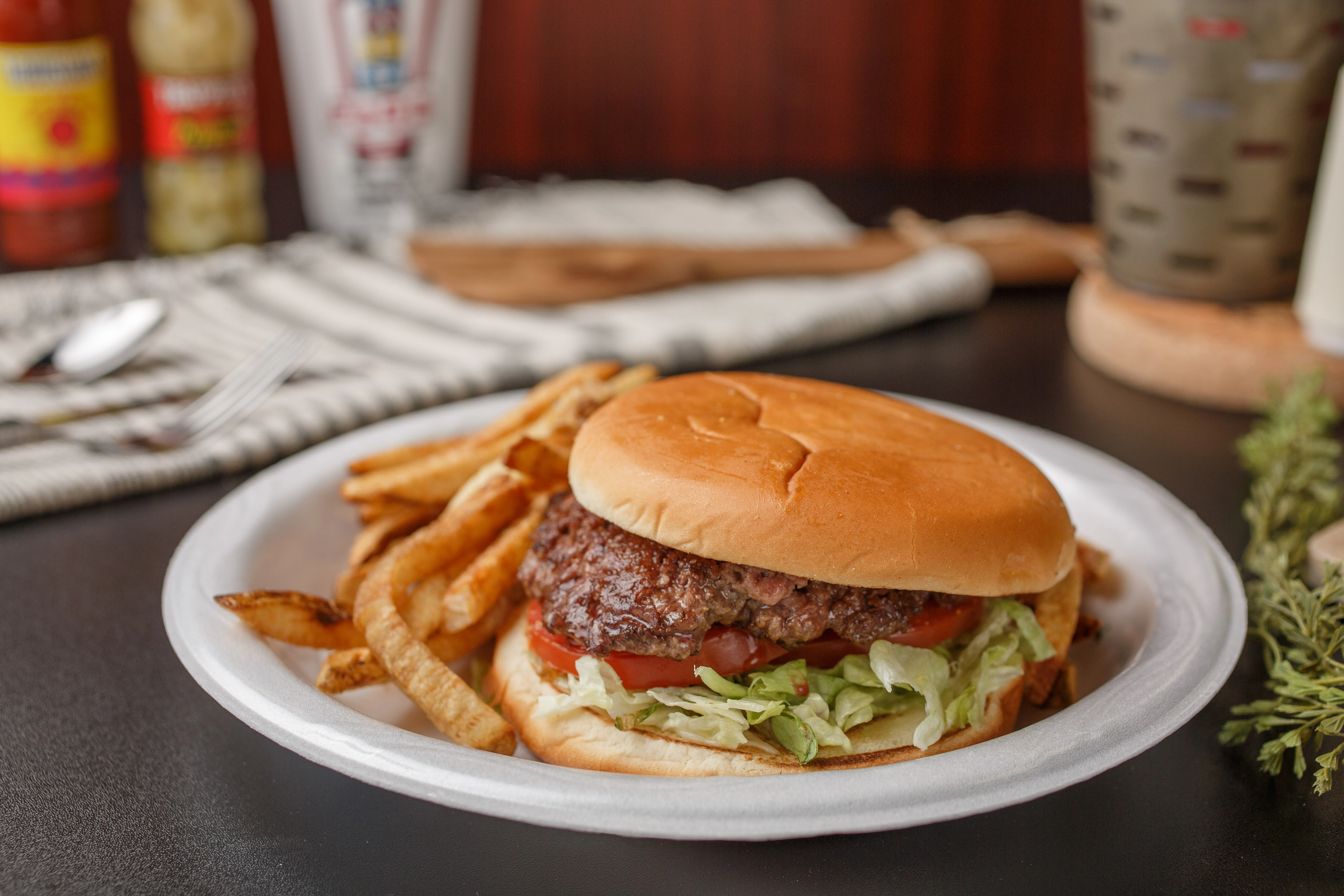 A delicious hamburger with lettuce, tomato, and fries on a plate.