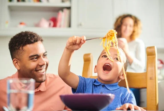 Child enjoying spaghetti at a family dinner