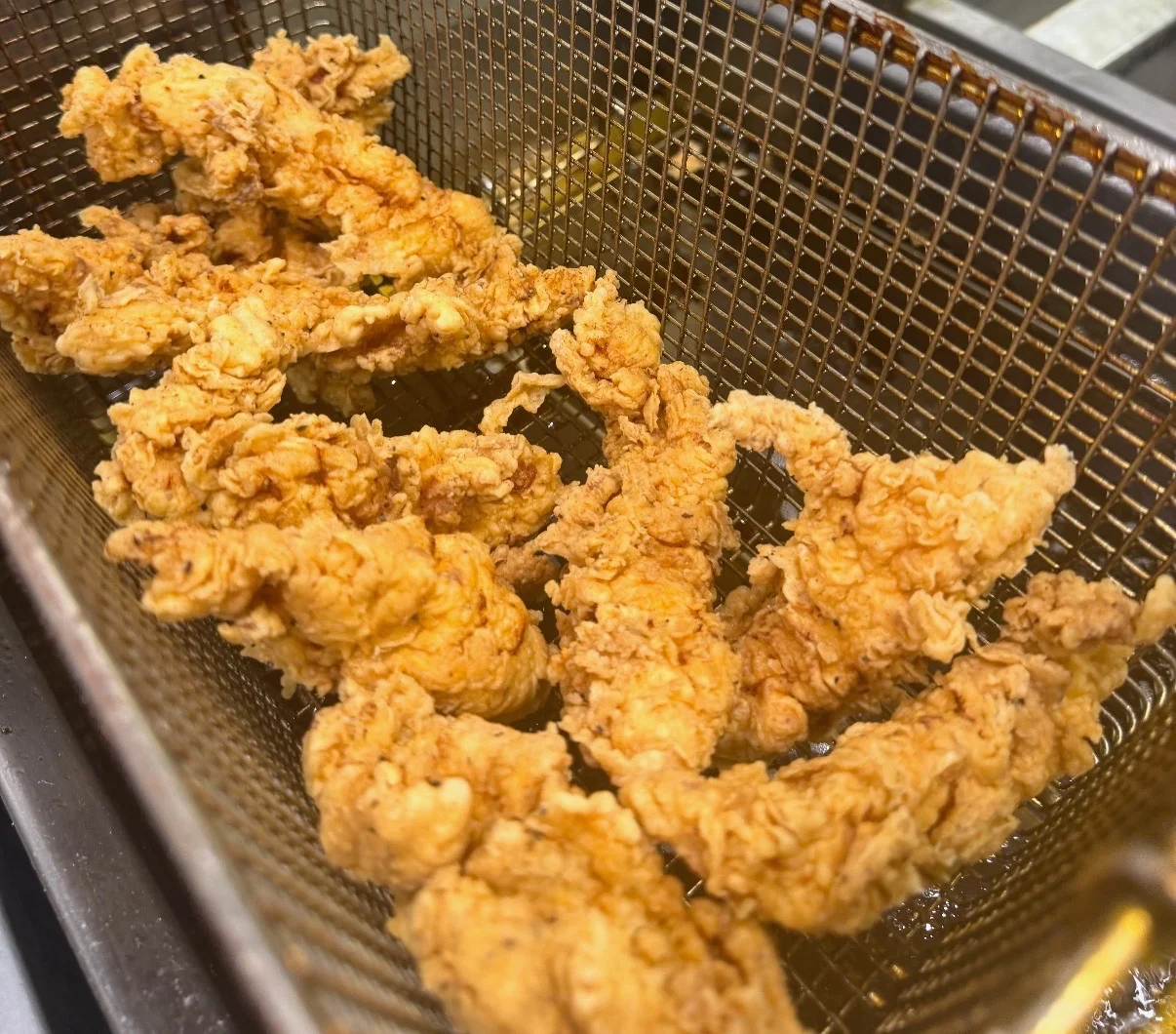 A close-up view of freshly fried chicken tenders in a basket.