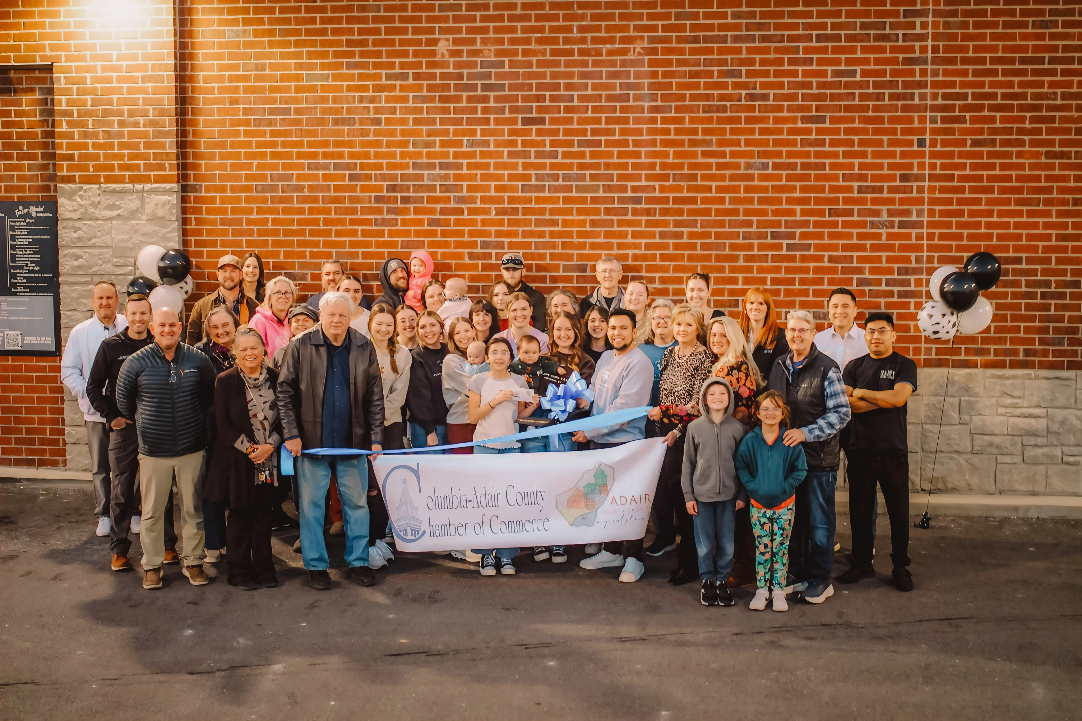Community gathering for a ribbon-cutting ceremony outside a restaurant