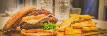 Juicy cheeseburger with fries on a wooden board