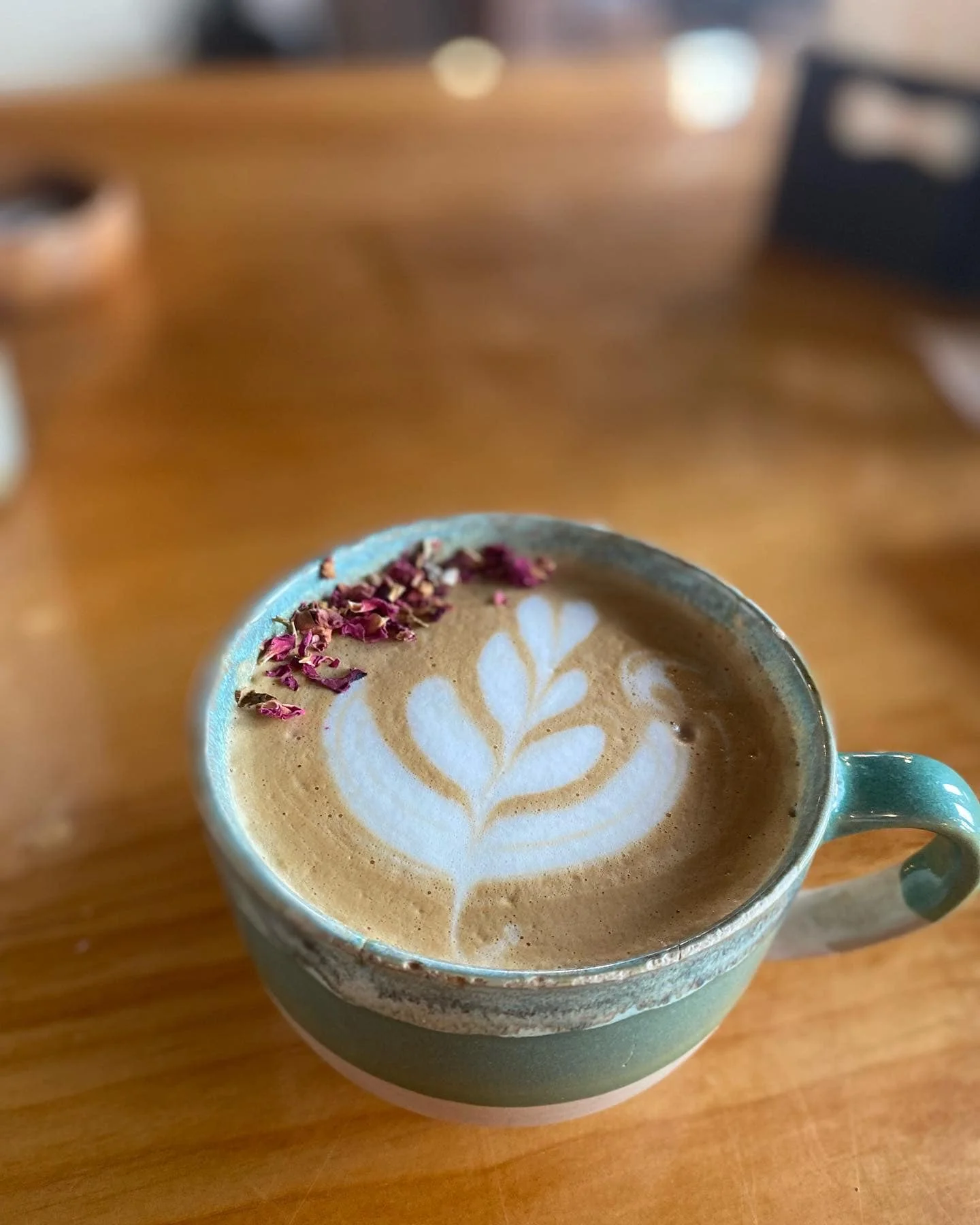 Artisan latte with floral design and rose petals