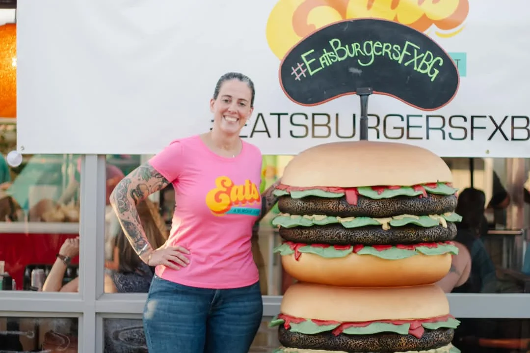 Restaurant owner posing with giant burger display