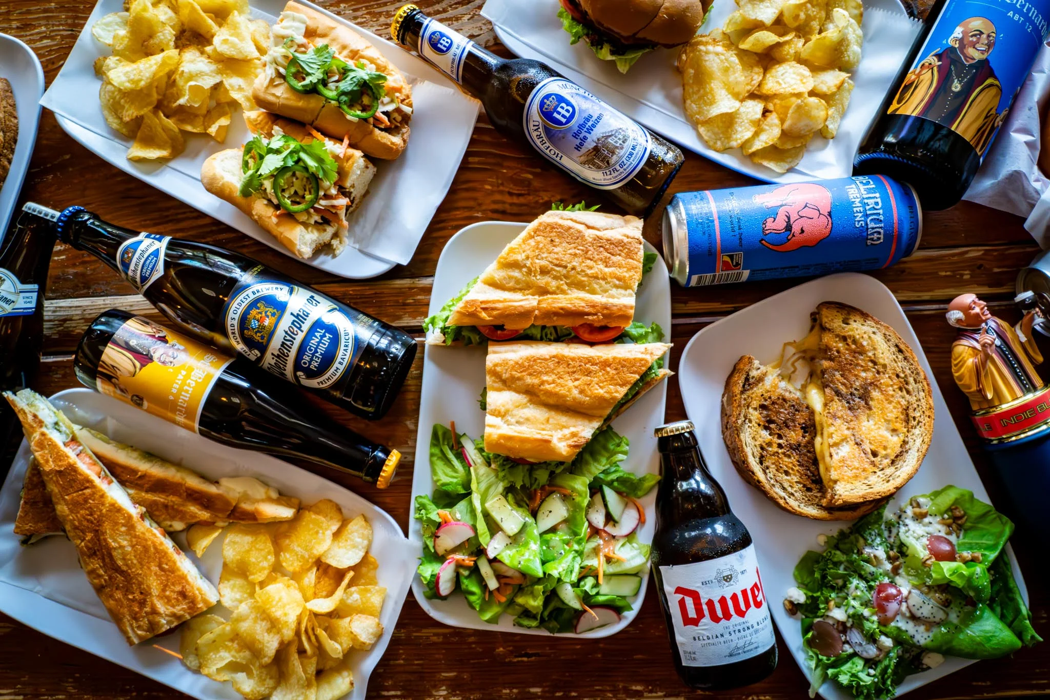 Assorted sandwiches and beers on a rustic wooden table