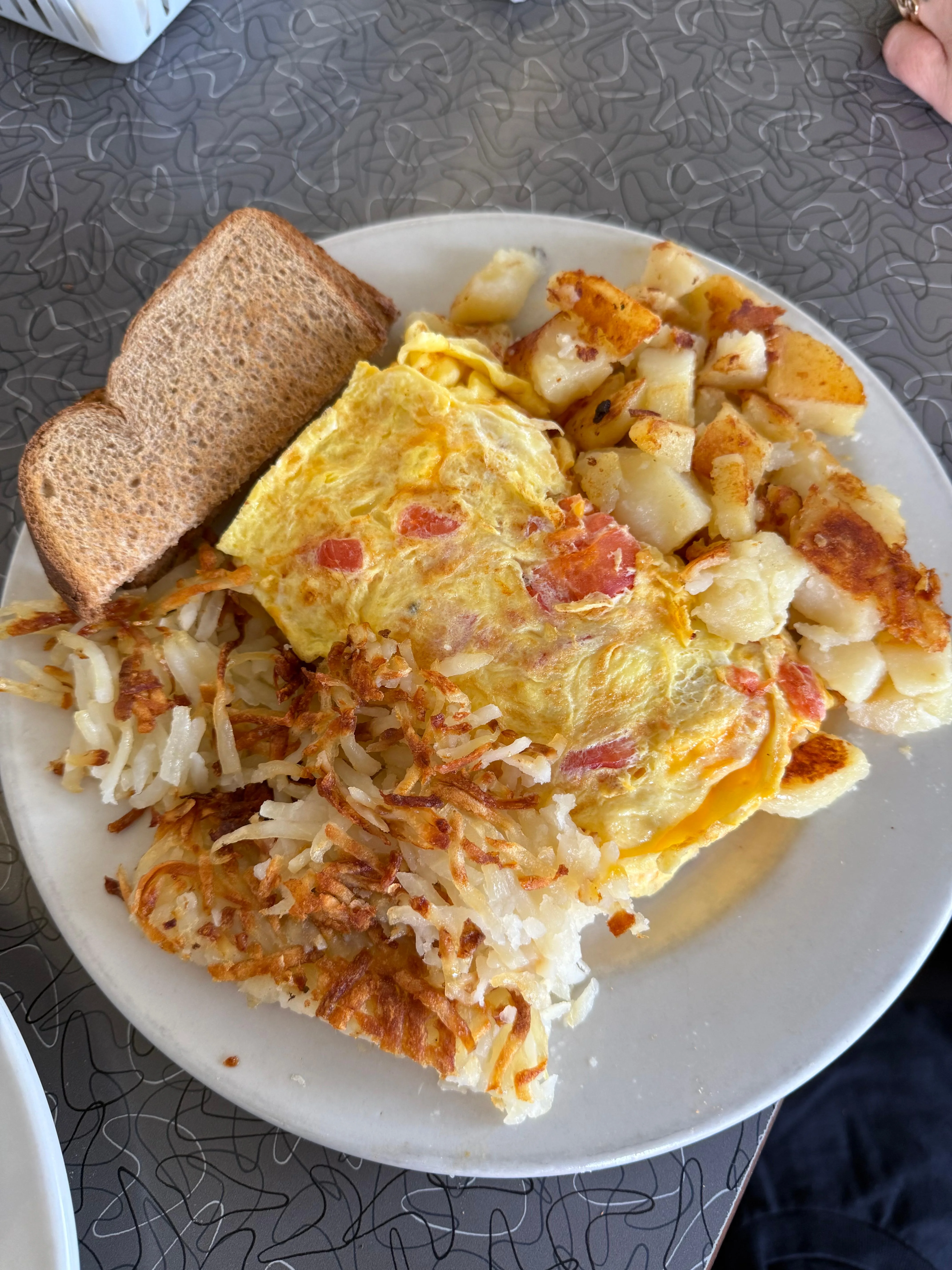 Moonlite Diner cheese omelet with tomatoes, crispy hash browns, home fries, and wheat toast served as a classic American breakfast.