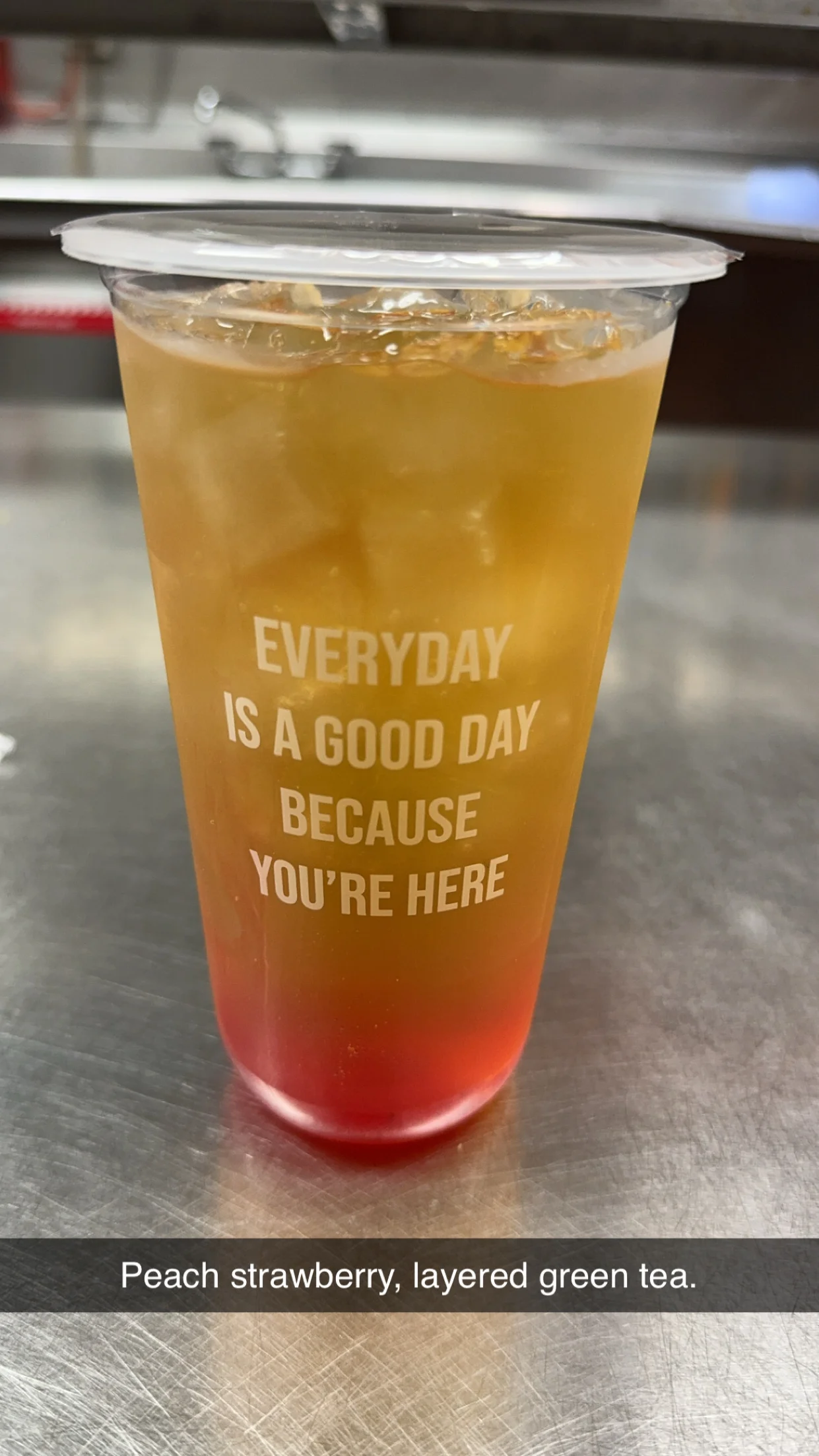 Layered peach strawberry green tea in a clear cup