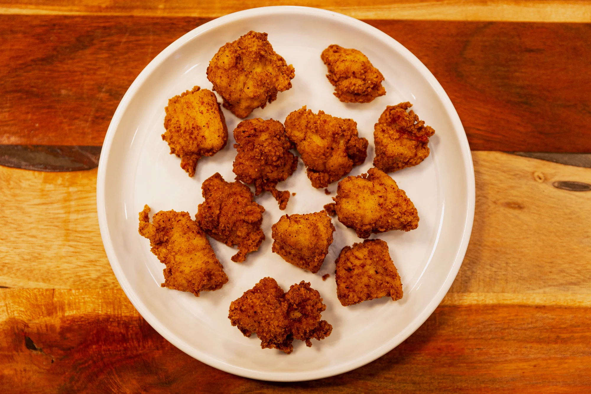 Chicken nuggets on a white plate.
