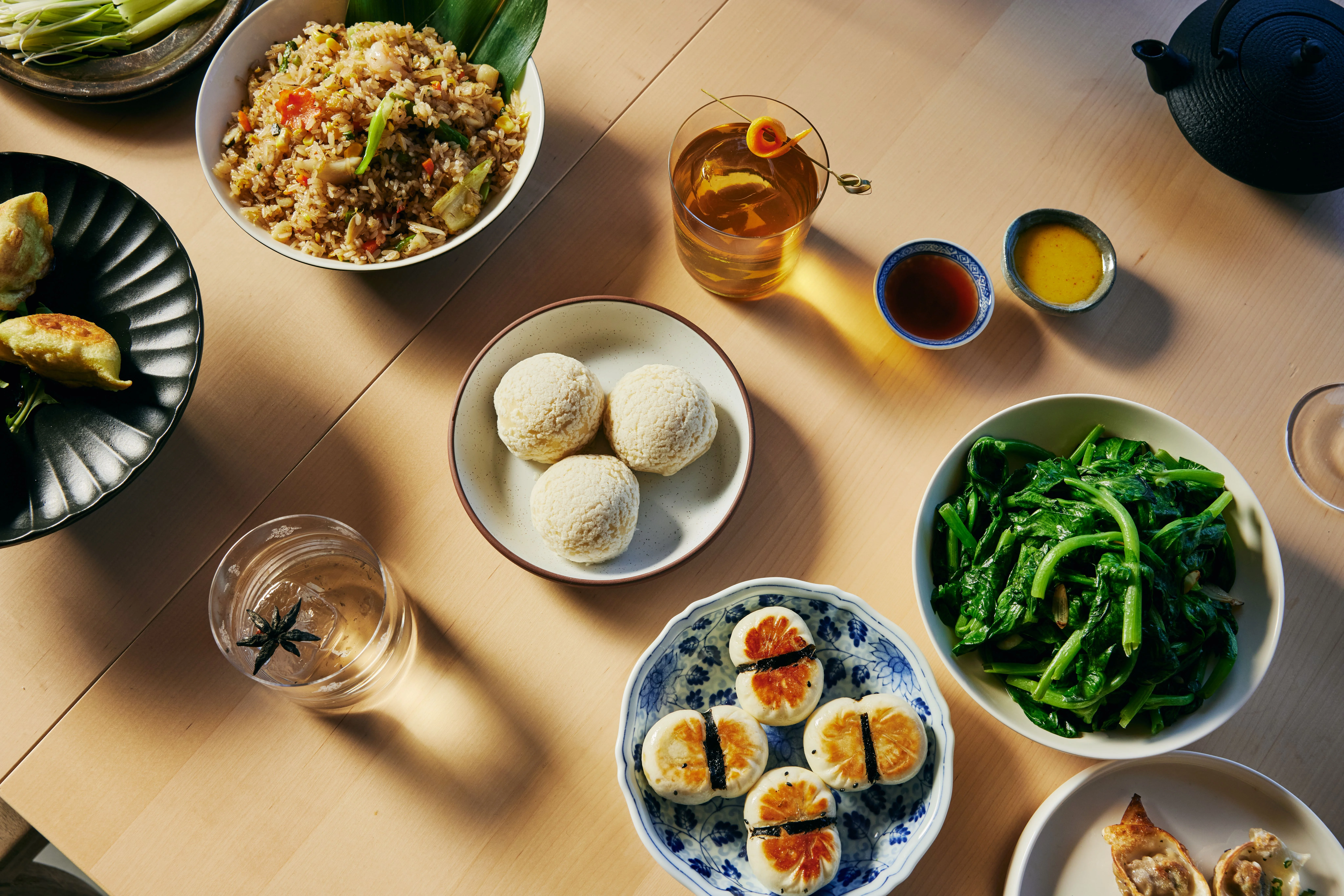 Assorted Asian dishes including bao buns and stir-fried greens
