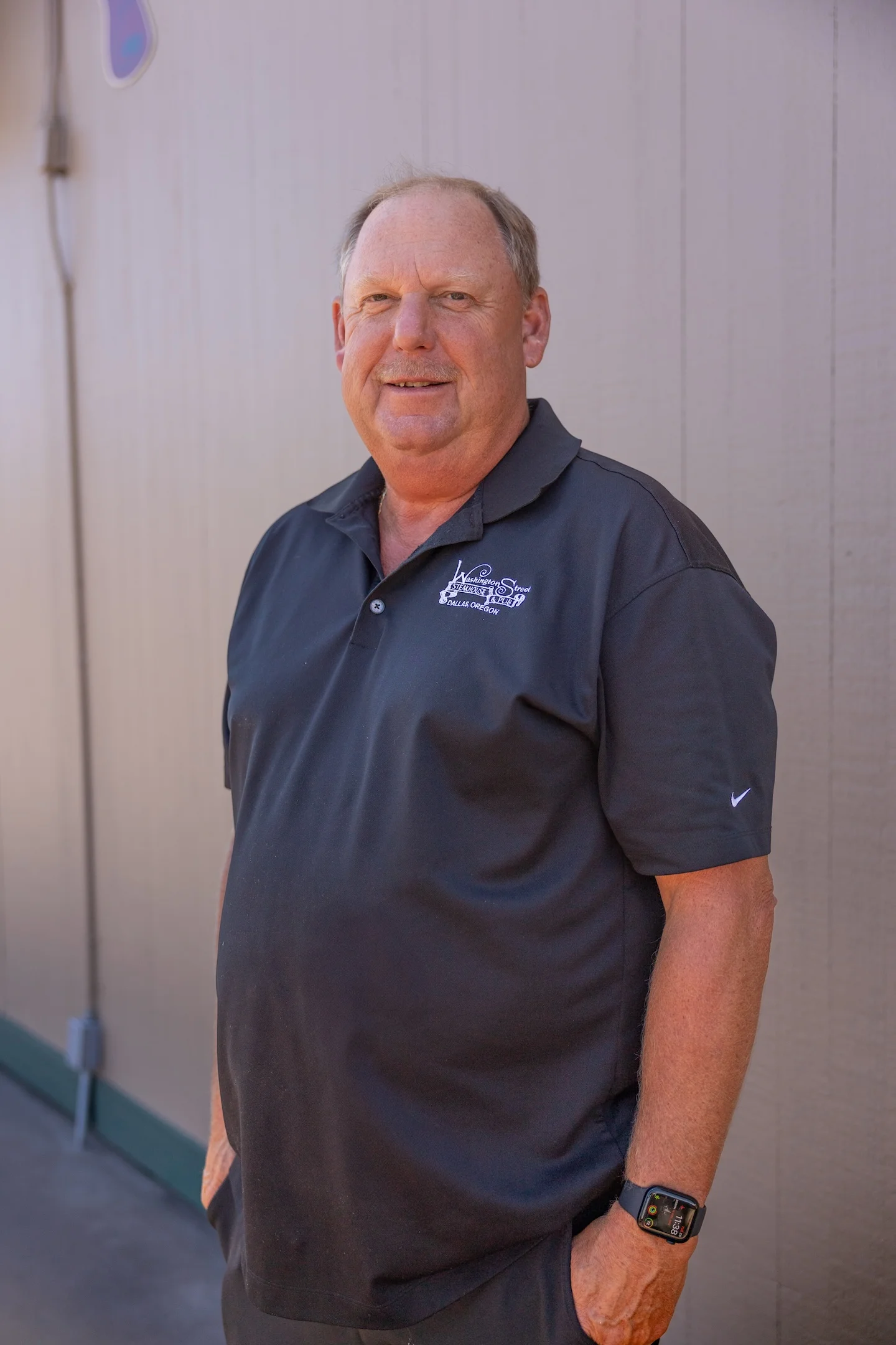 Smiling restaurant owner in a black polo shirt