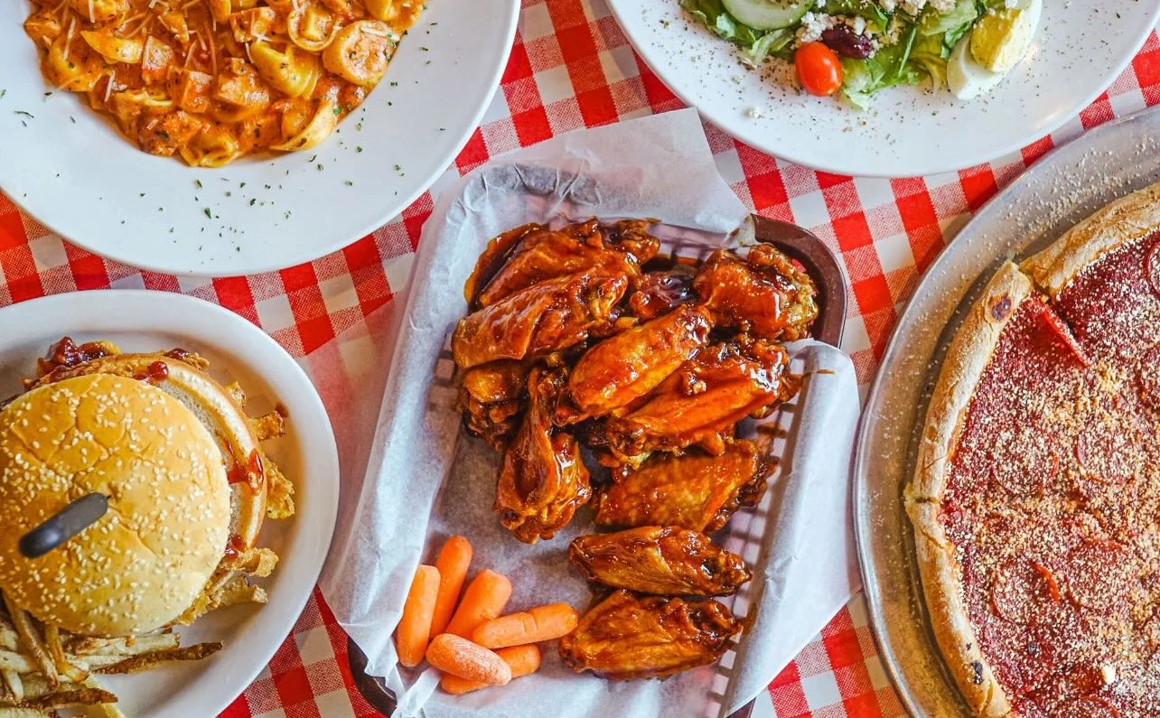 Assorted American comfort food platter with wings, burger, and pizza