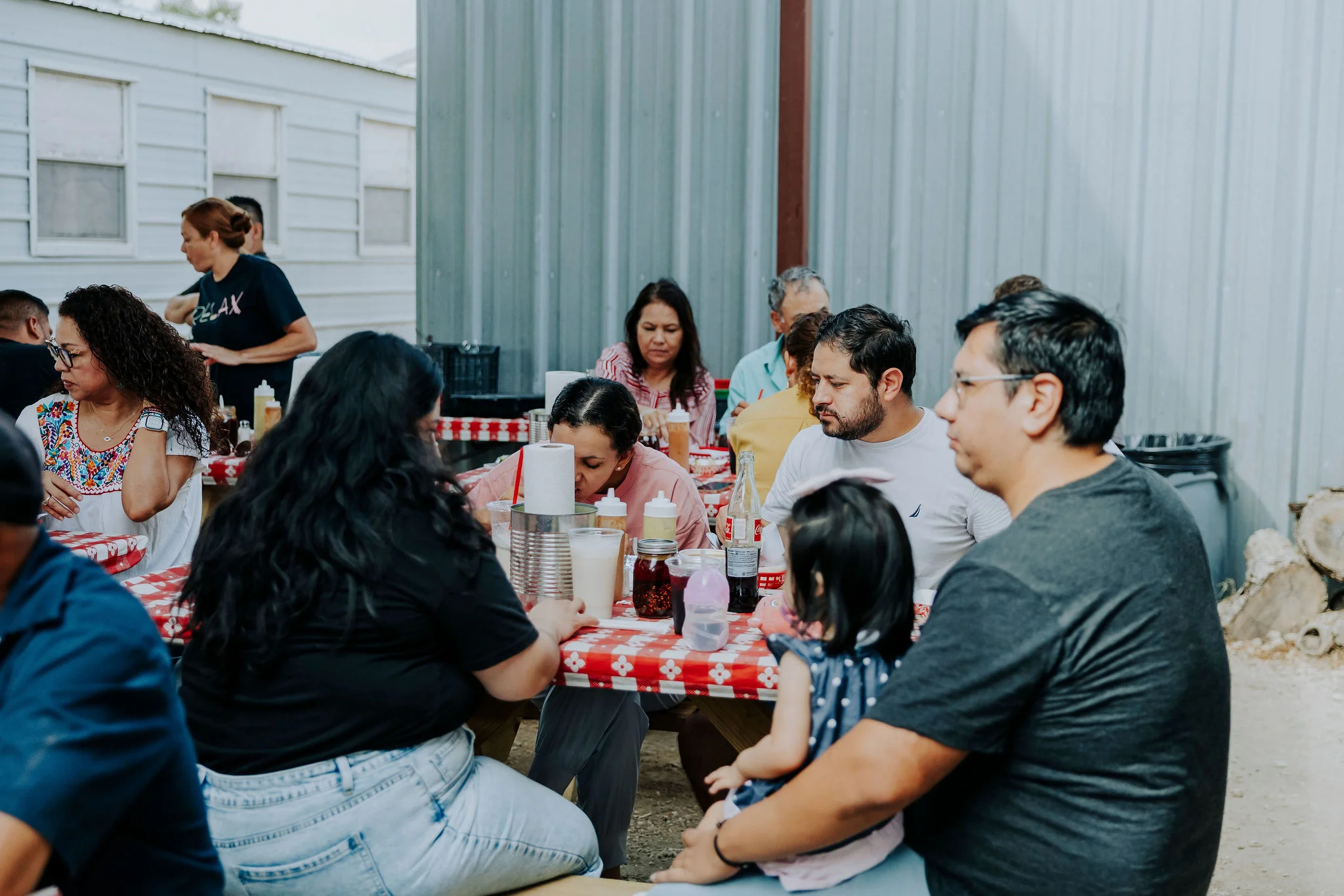 Casual dining scene with families enjoying food at picnic-style tables.