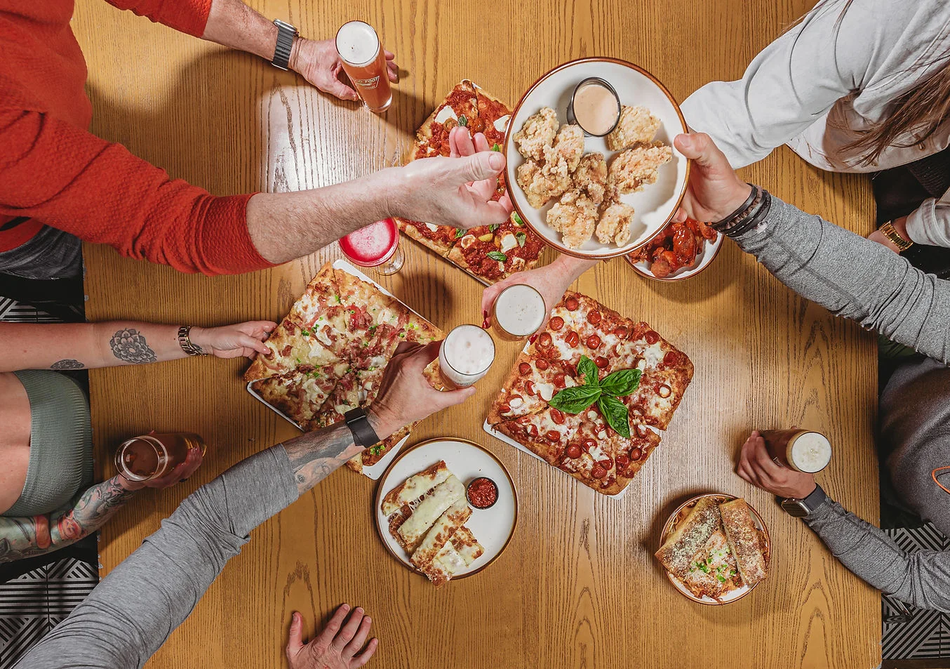 Gathering around a table with various pizzas and appetizers