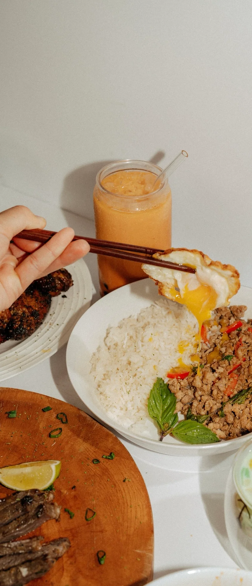 A spread of delicious Lao comfort food, including grilled chicken wings, fried rice, dumplings, and spring rolls, arranged on various plates.