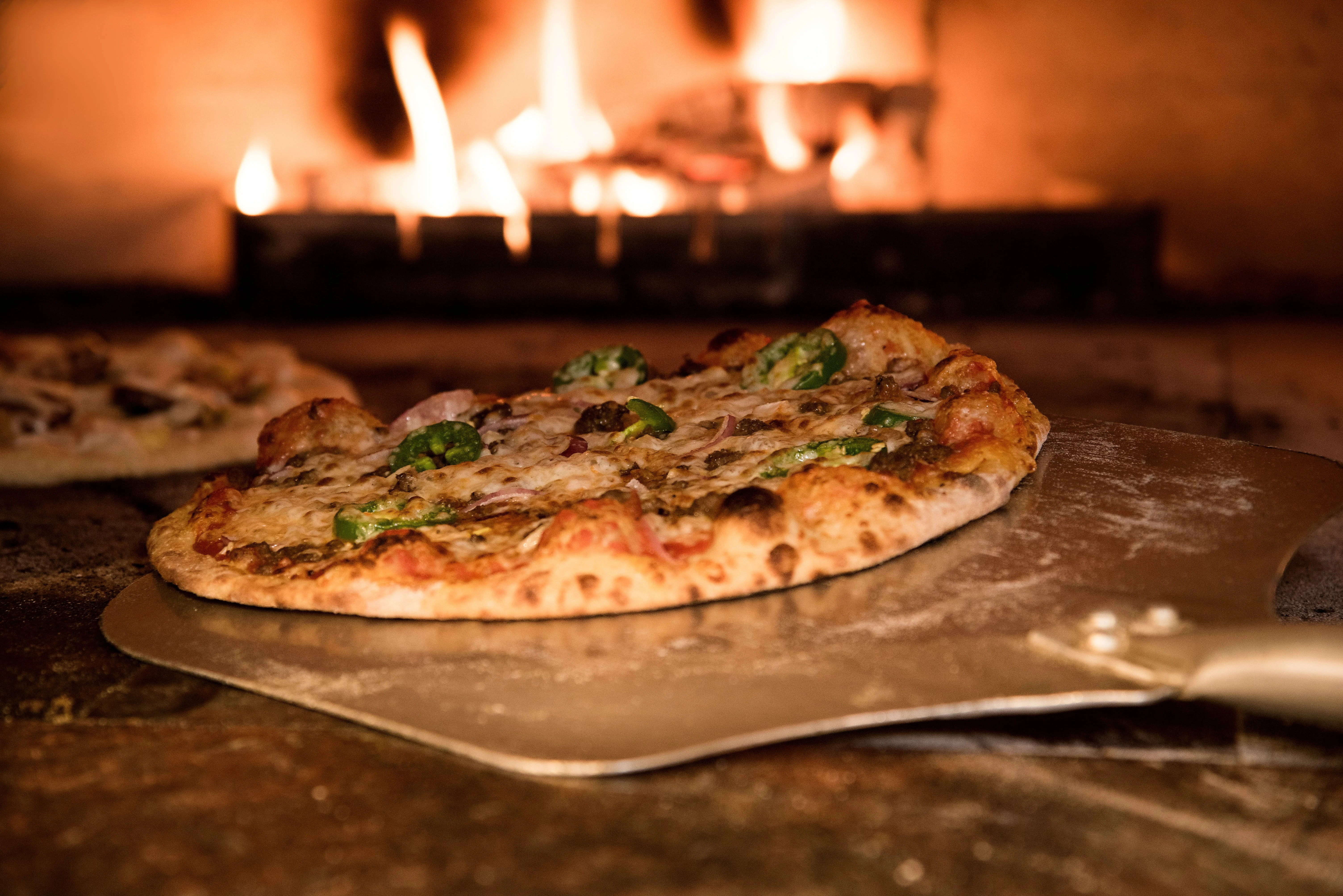 Artisan pizza cooking in an oven, about to be served to patrons 