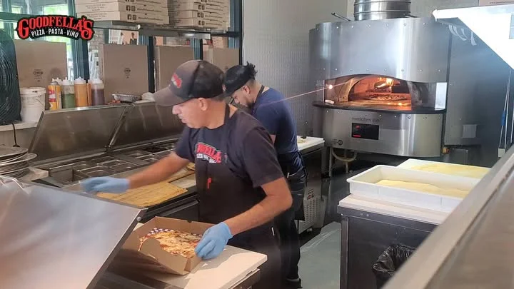 Pizza being prepared in a bustling pizzeria kitchen