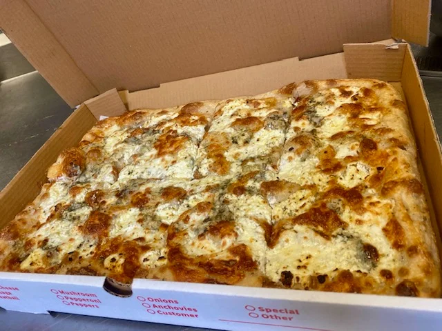 Square Sicilian pizza with golden crust and melted cheese