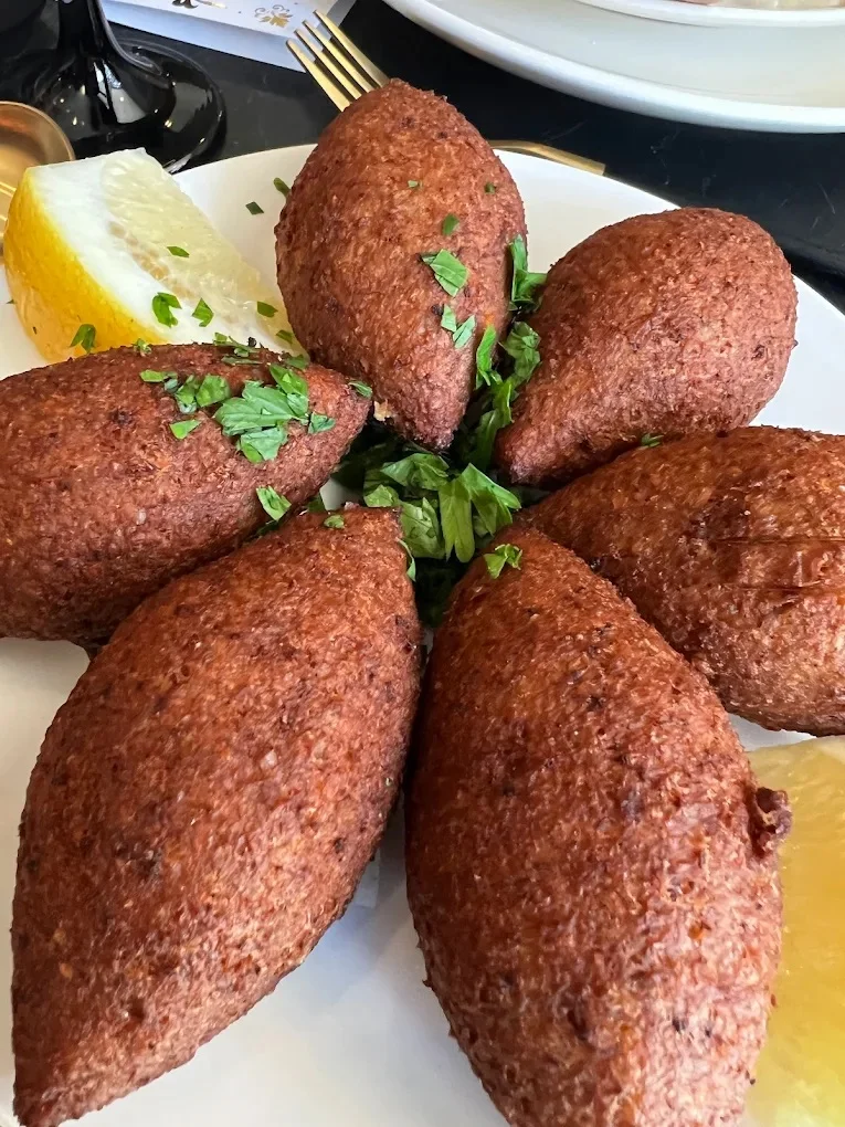 Plate of kibbeh served with lemon and parsley garnish.