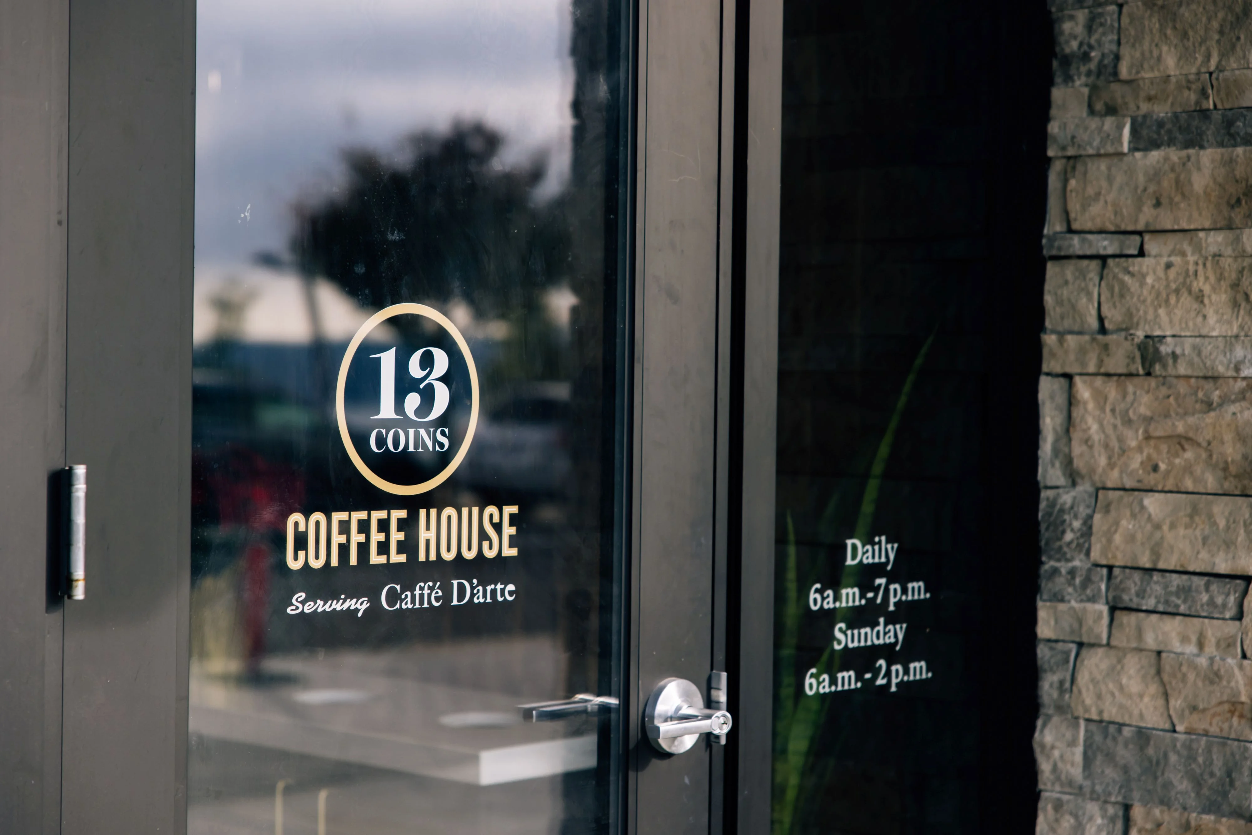 Entrance of 13 Coins Coffee House with operating hours displayed.