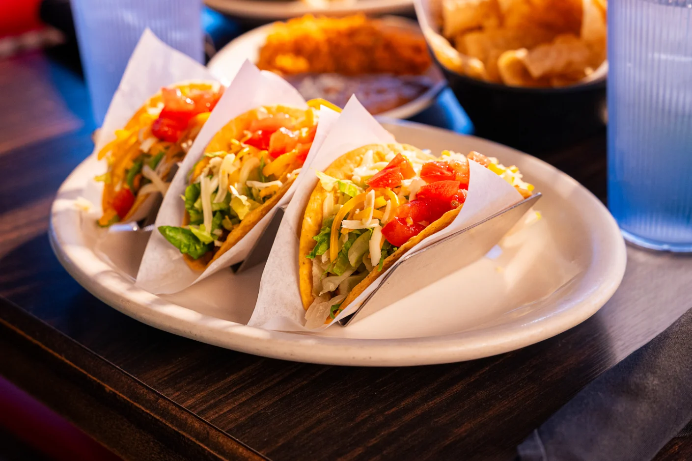 Three delicious tacos served on a plate in a vibrant restaurant setting
