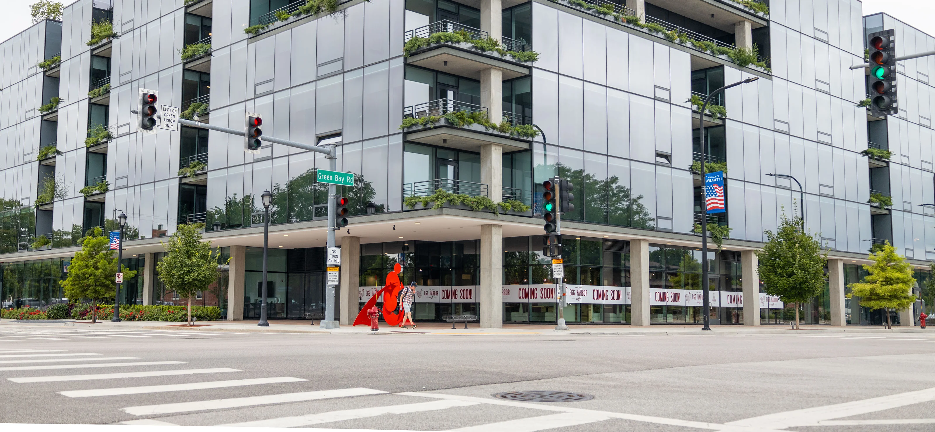 Modern glass building with greenery and art installation