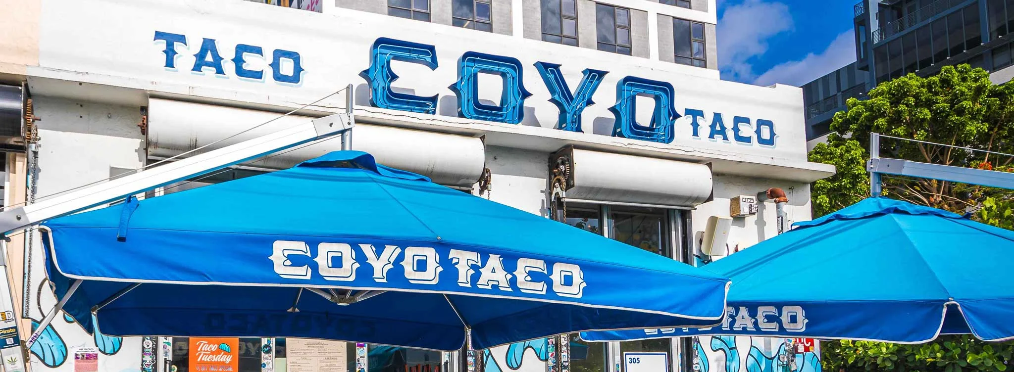 Colorful taco restaurant exterior with blue umbrellas