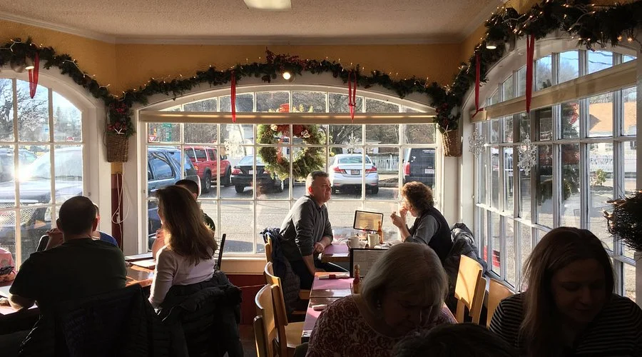 Sunlit restaurant dining room with holiday garlands and seated guests