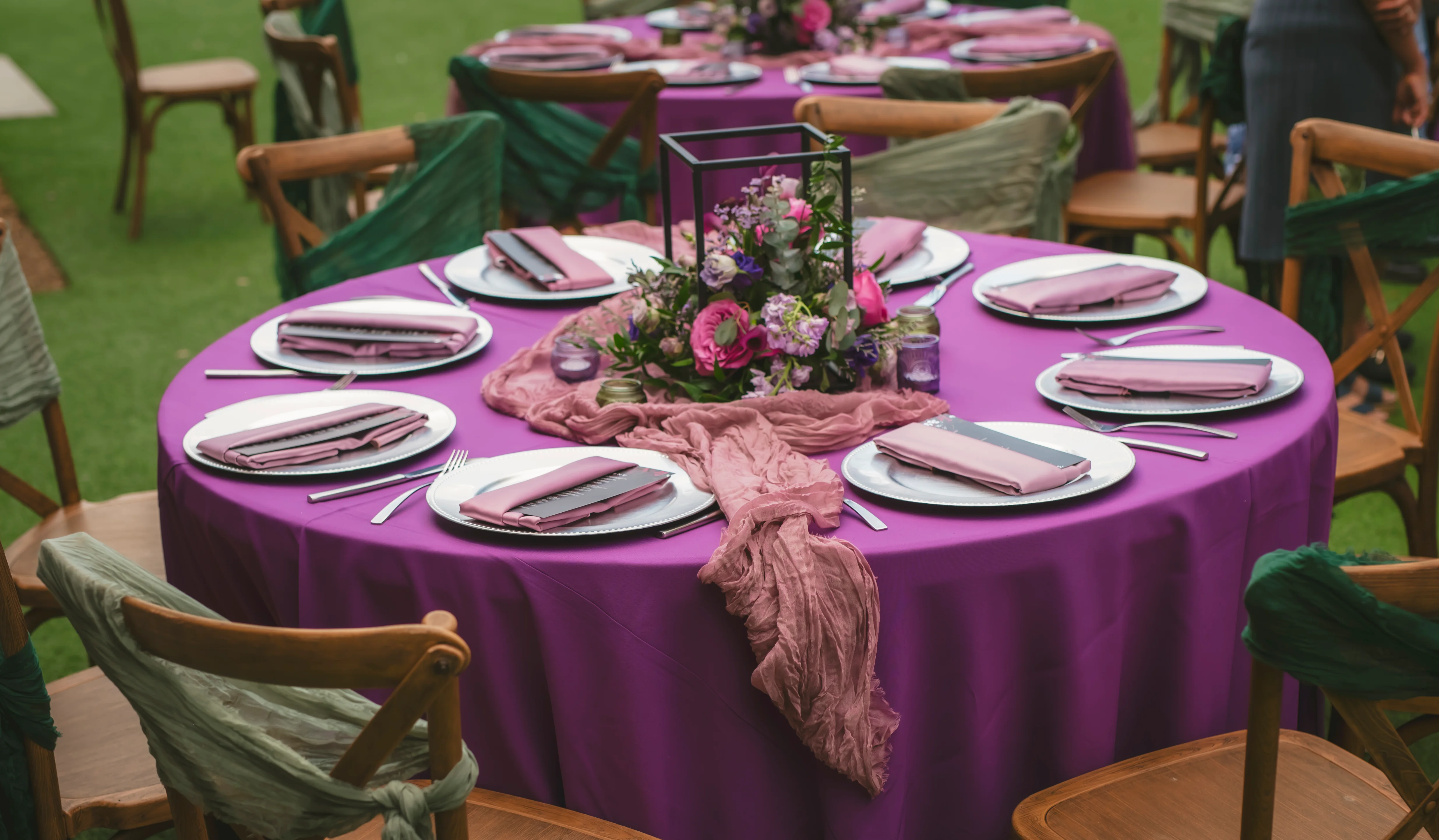 Elegant outdoor dining setup with purple tablecloth and floral centerpiece
