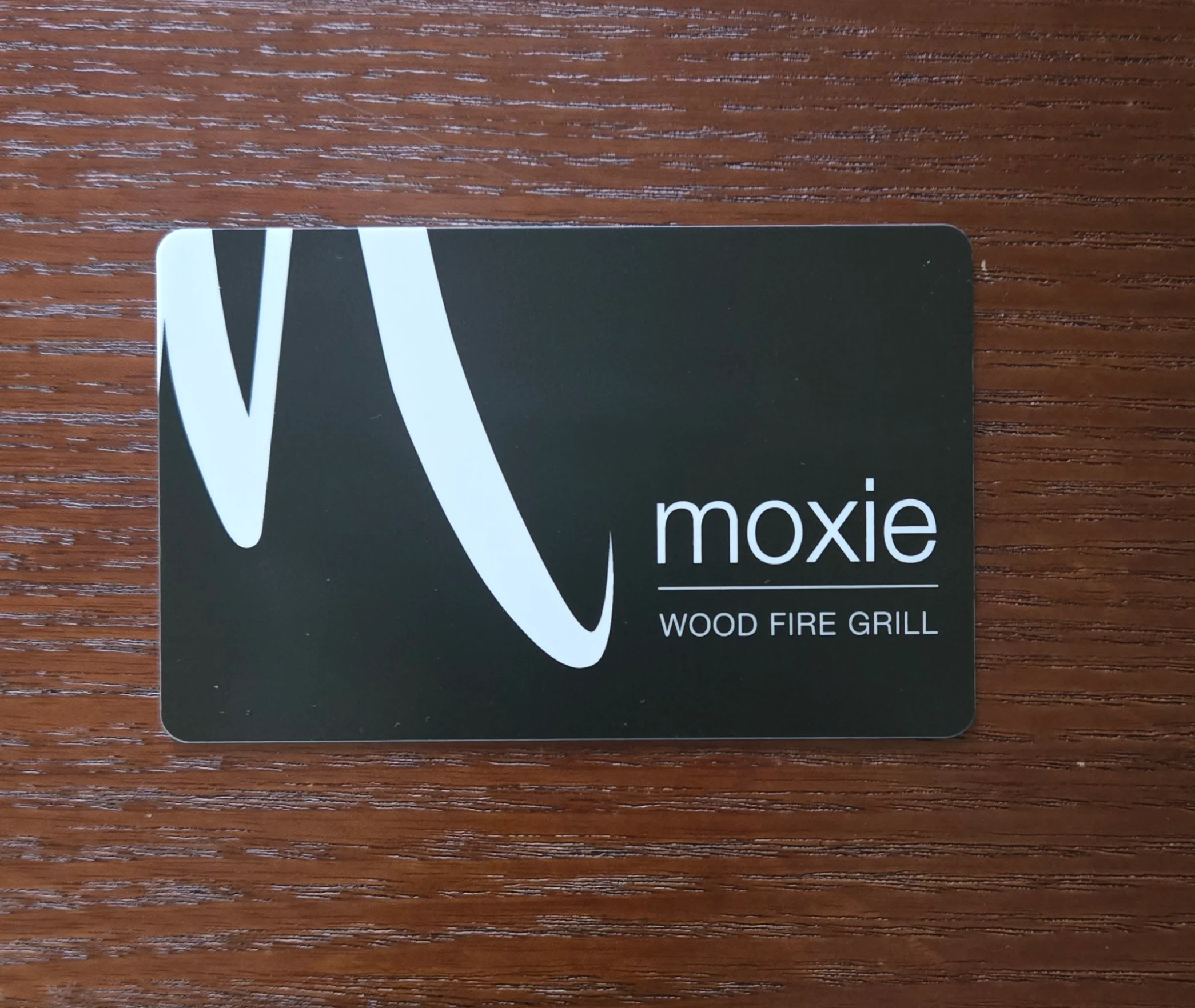 Moxie Wood Fire Grill gift card on a wooden surface